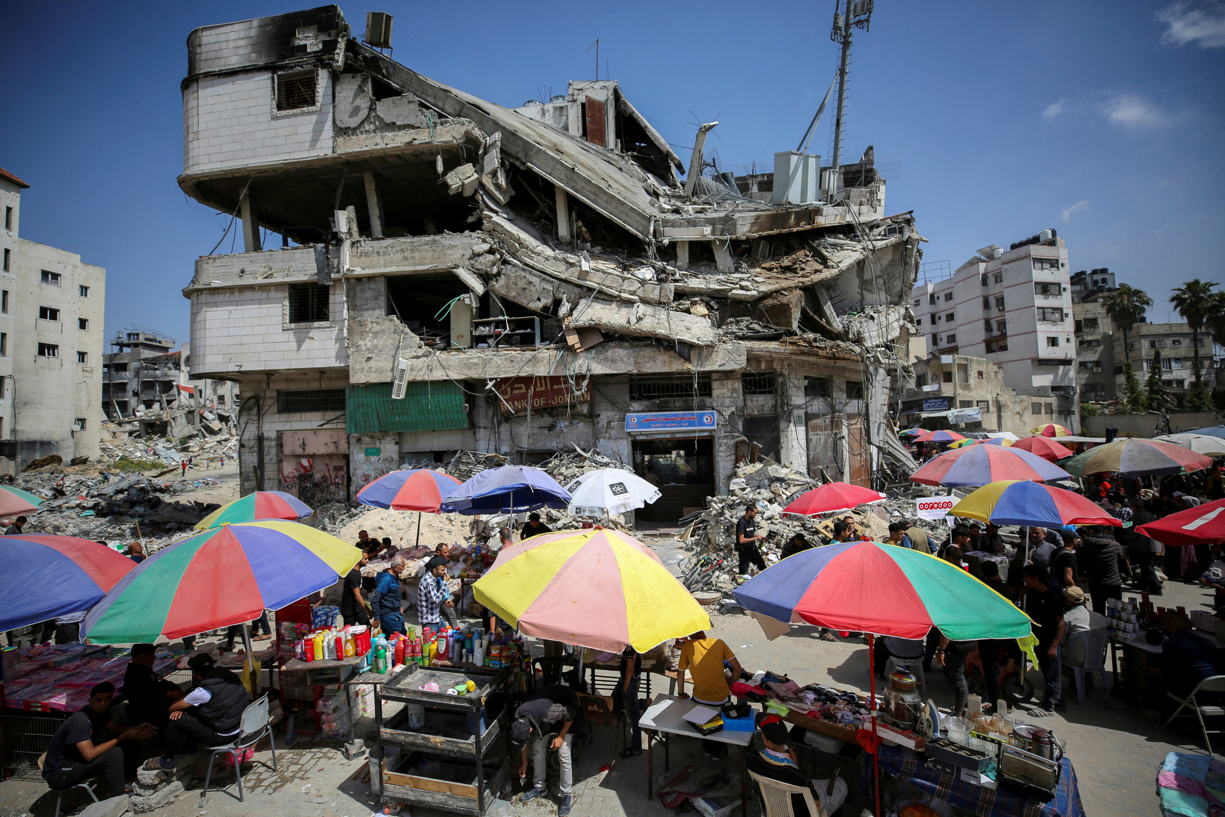 Palestinian vendors sell goods near a destroyed building in Gaza City on May 5. Photo: Reuters