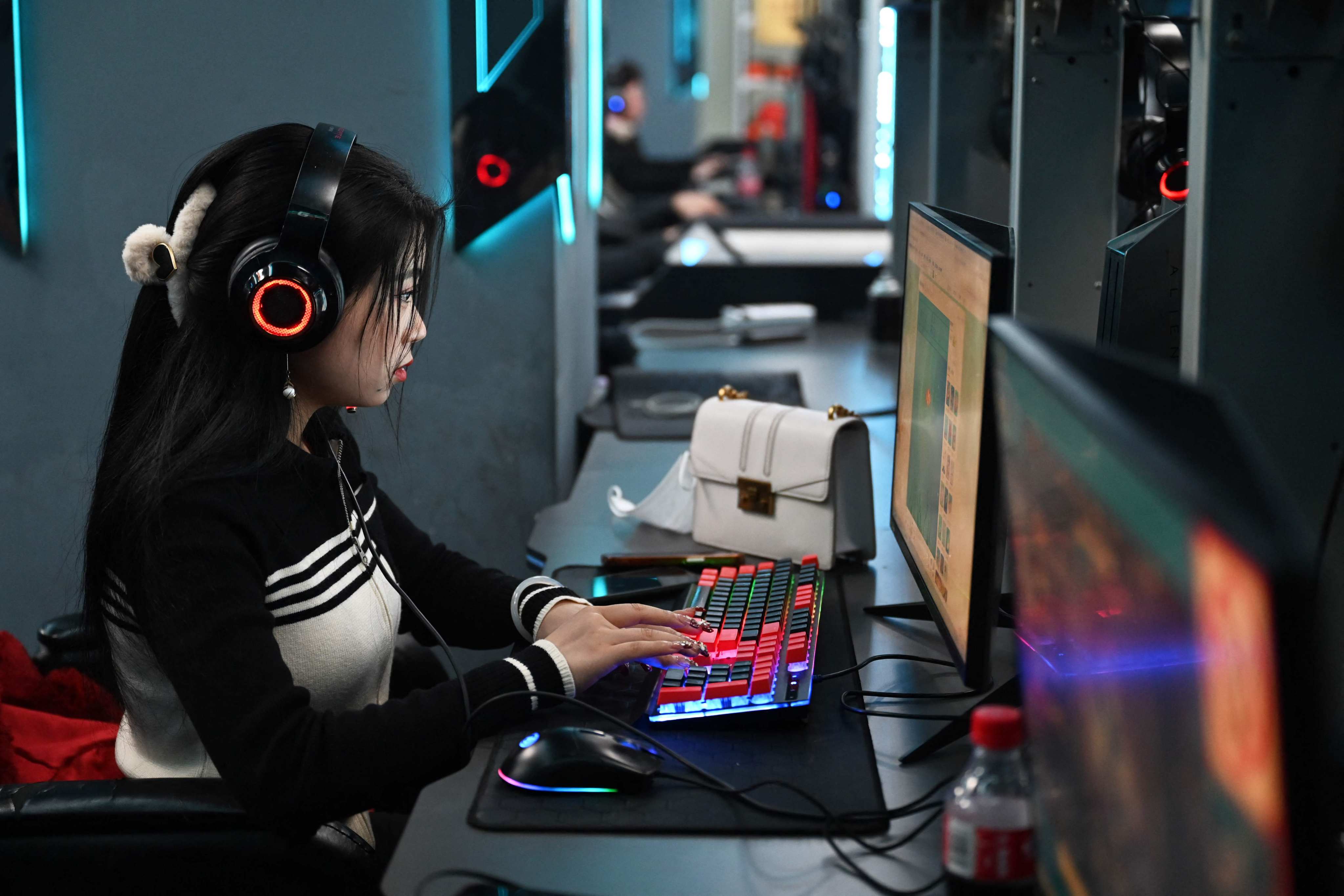A woman plays computer games at an internet cafe in Beijing, January 26, 2024. Photo: AFP