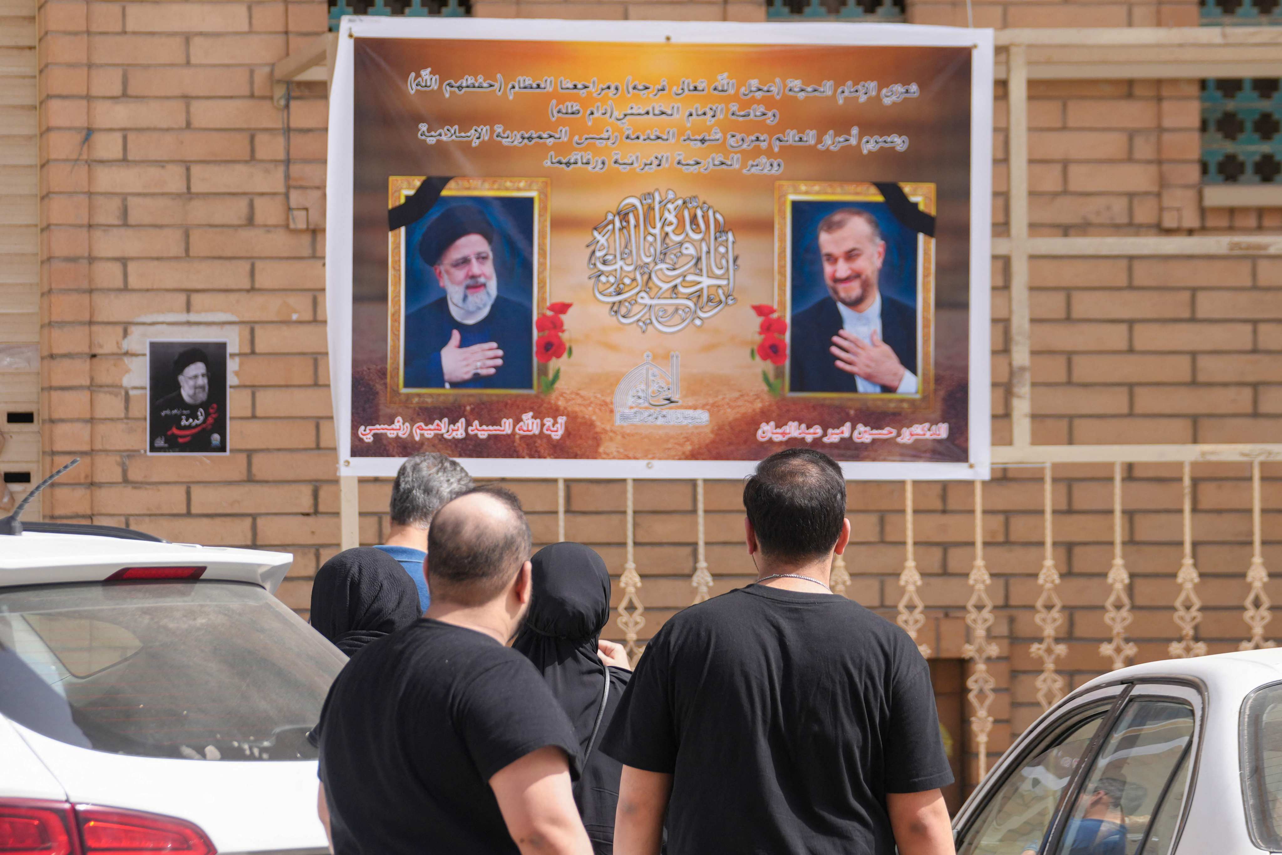 People walk in the central Iraqi holy city of Najaf, past portraits of Iran’s President Ebrahim Raisi (left) and Foreign Minister Hossein Amir-Abdollahian (right) who died in a helicopter crash on Monday. Photo: AFP
