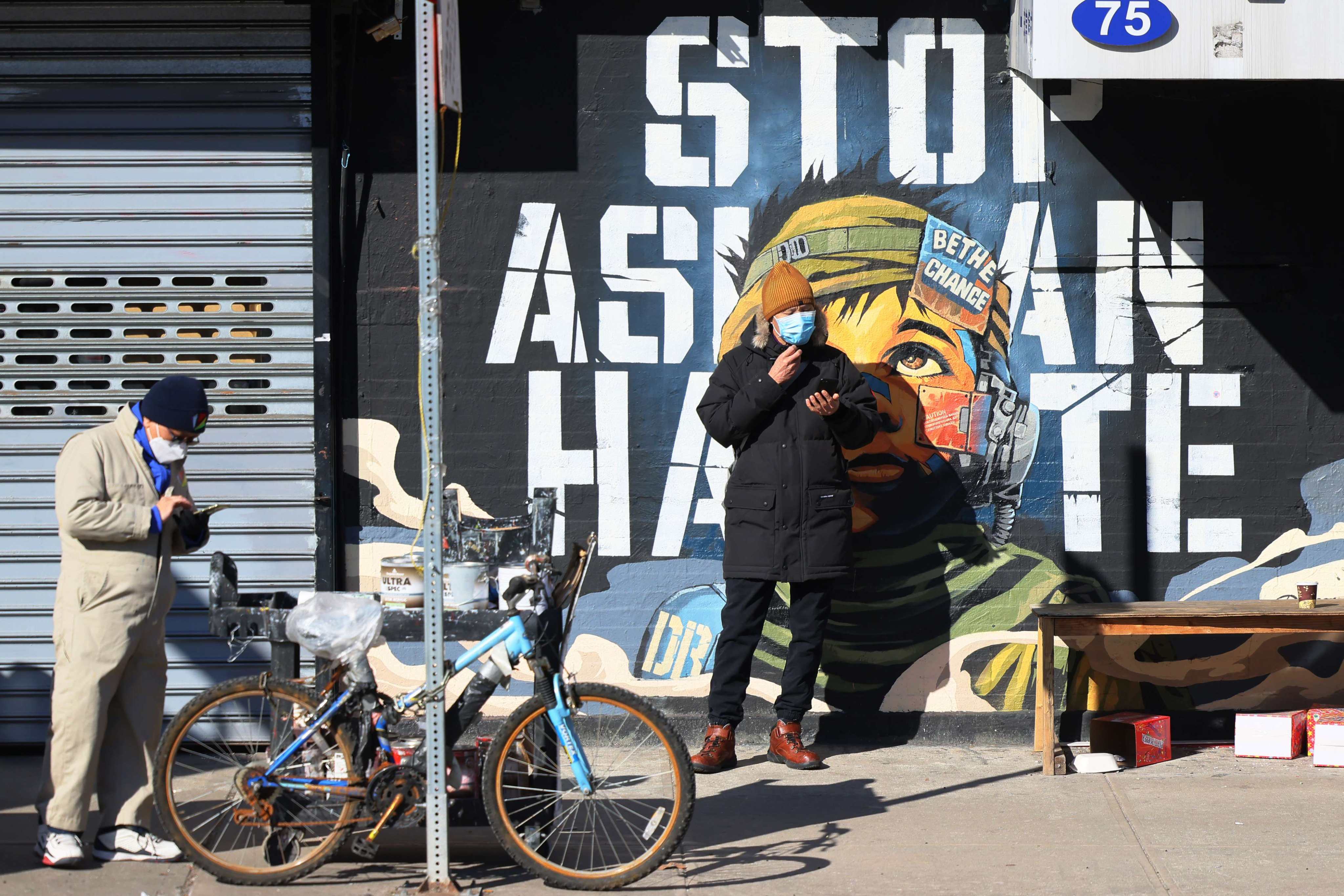 People stand in front of a “Stop Asian Hate” mural in New York in 2022. Photo: AFP