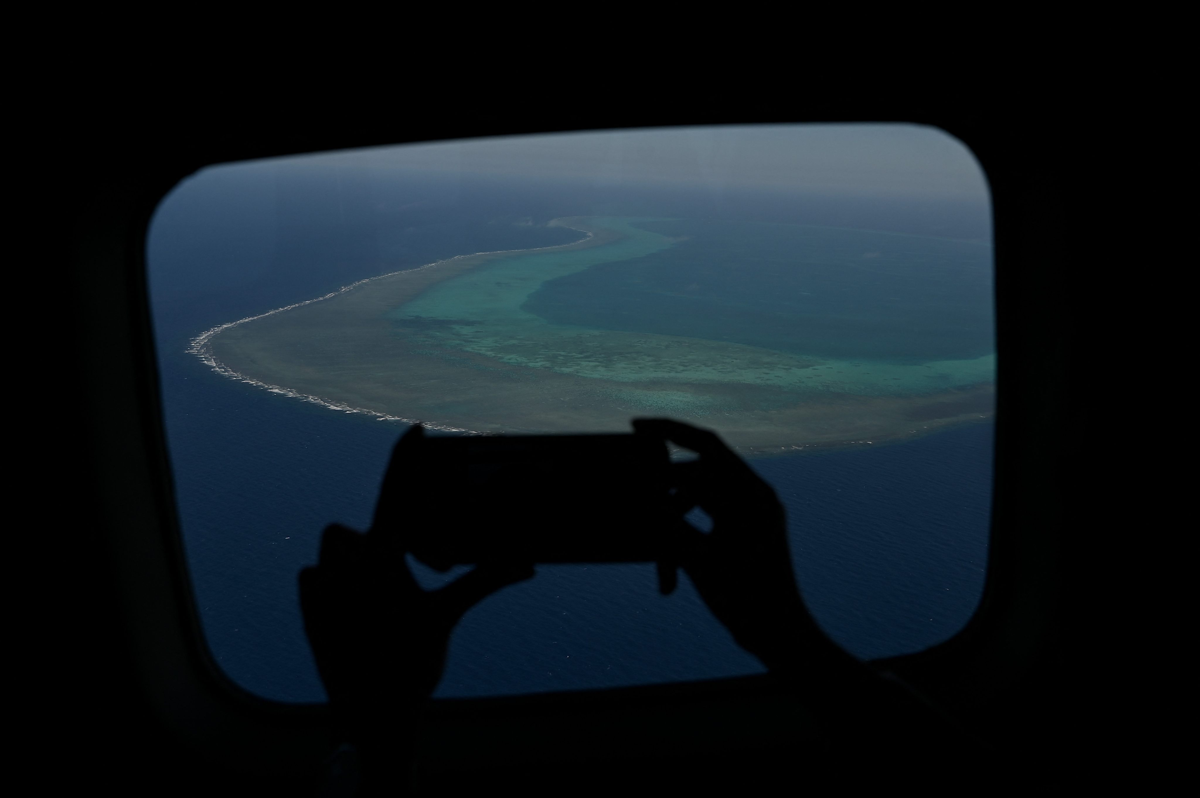 A reporter takes a photograph of the Scarborough Shoal from an aircraft flying over the South China Sea in February. Photo: AFP