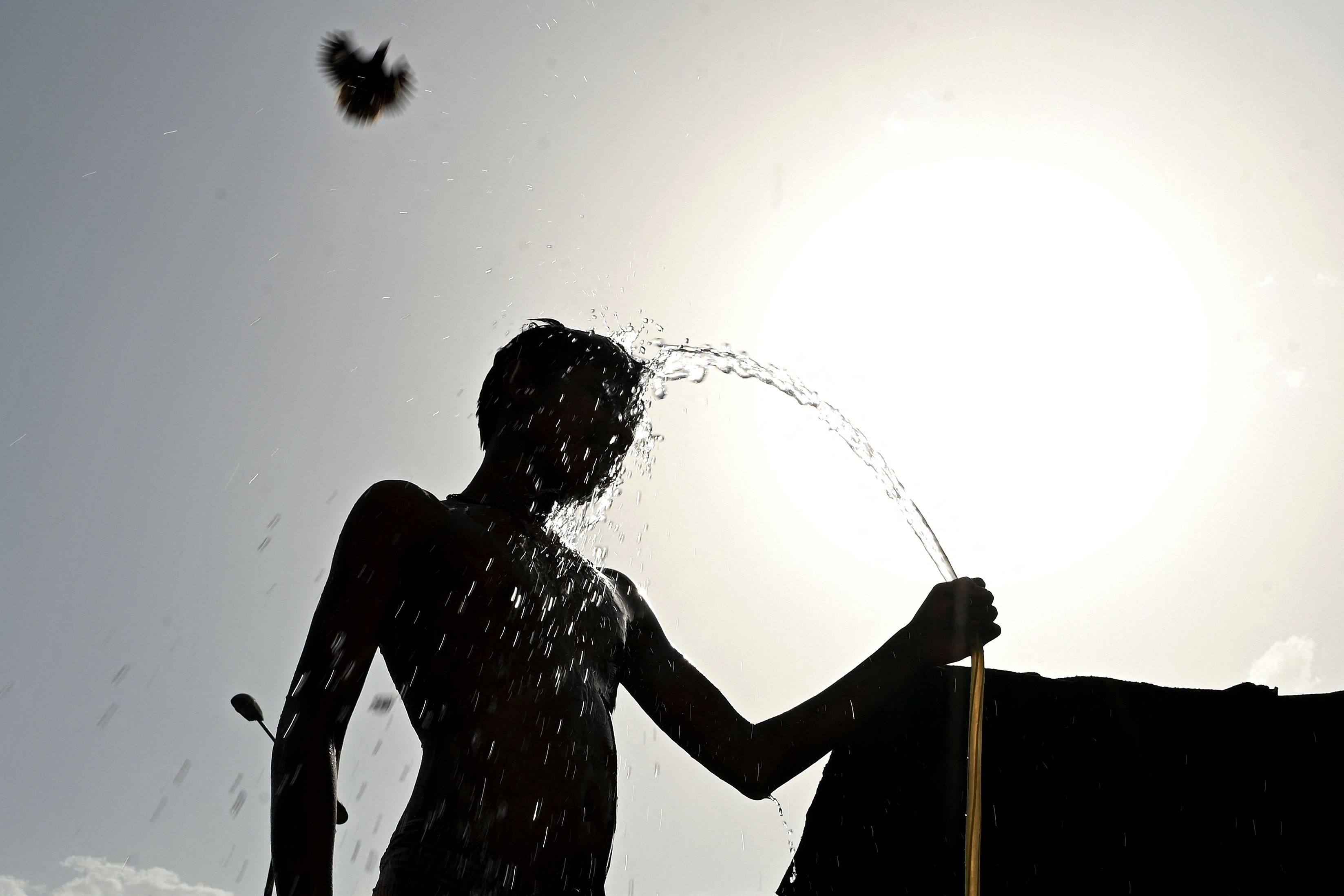 A man is silhouetted against the sun while taking a bath on a hot summer day in New Delhi on May 15. Photo: AFP