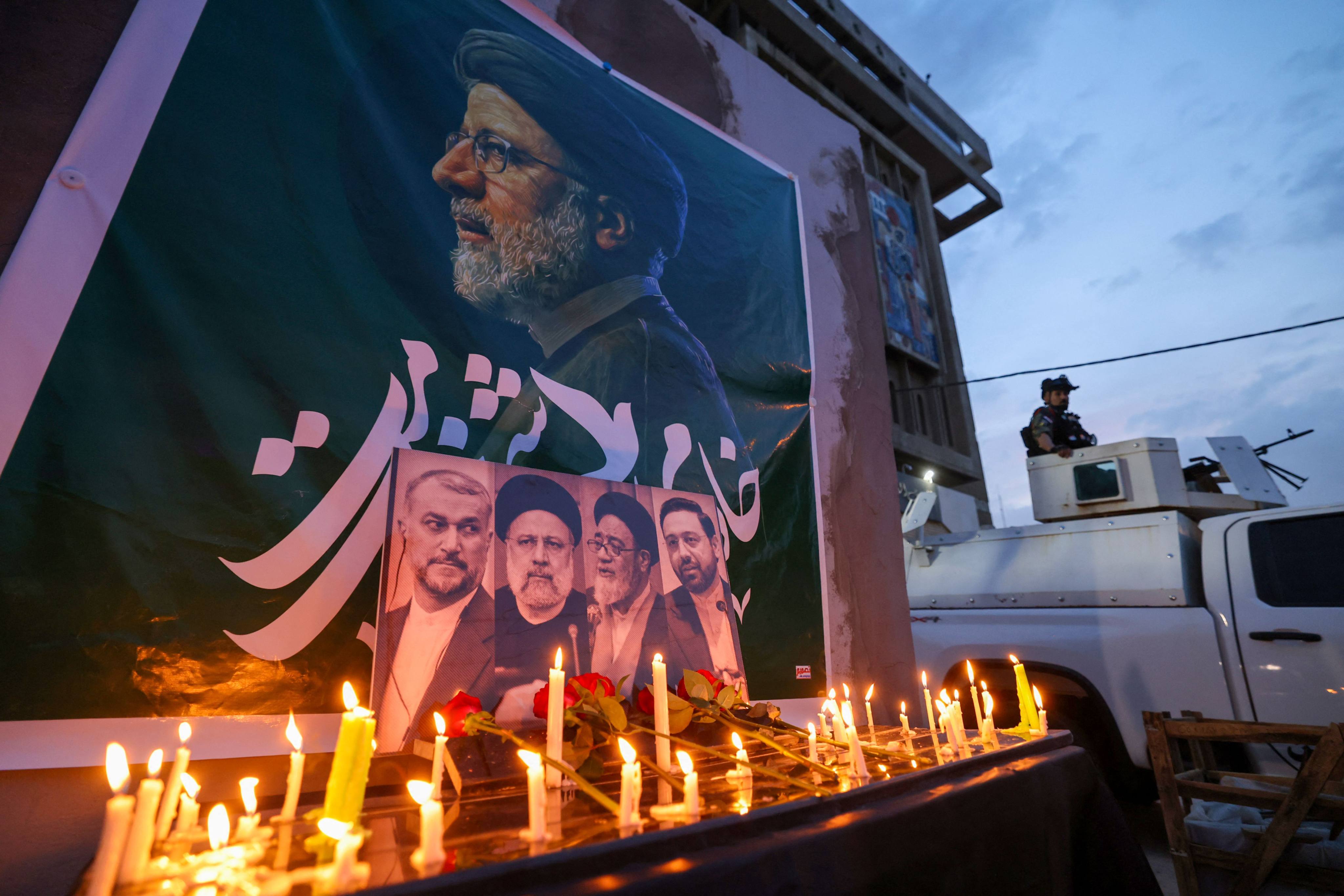 An Iraqi soldier stands guard next candles lit by people paying their respects to Iran’s late president Ebrahim Raisi outside the Iranian embassy in Baghdad on Monday. Photo: AFP