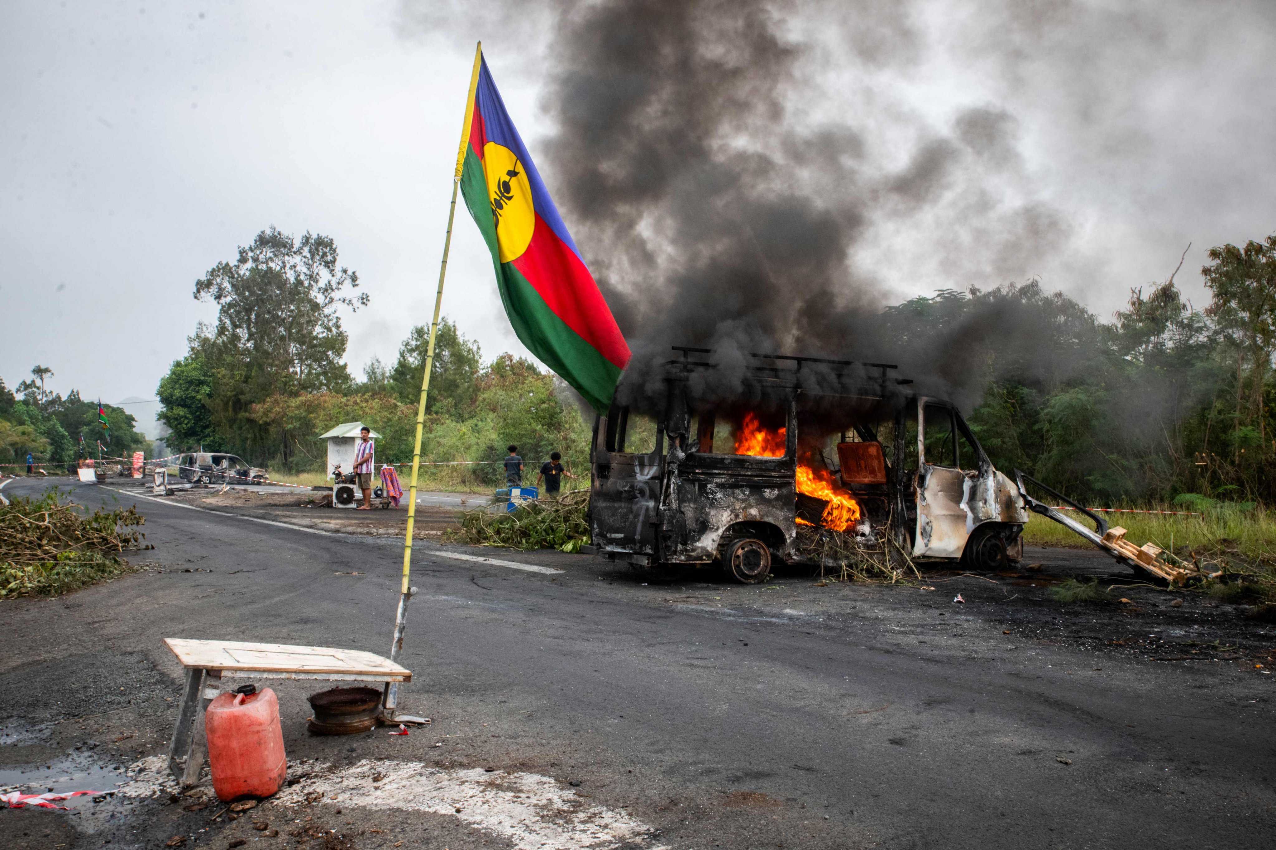 A Kanak flag is seen waving next to a burnt-out vehicle at a roadblock in New Caledonia. Three of the six people killed in the unrest were indigenous Kanaks shot by armed civilians. Photo: AFP