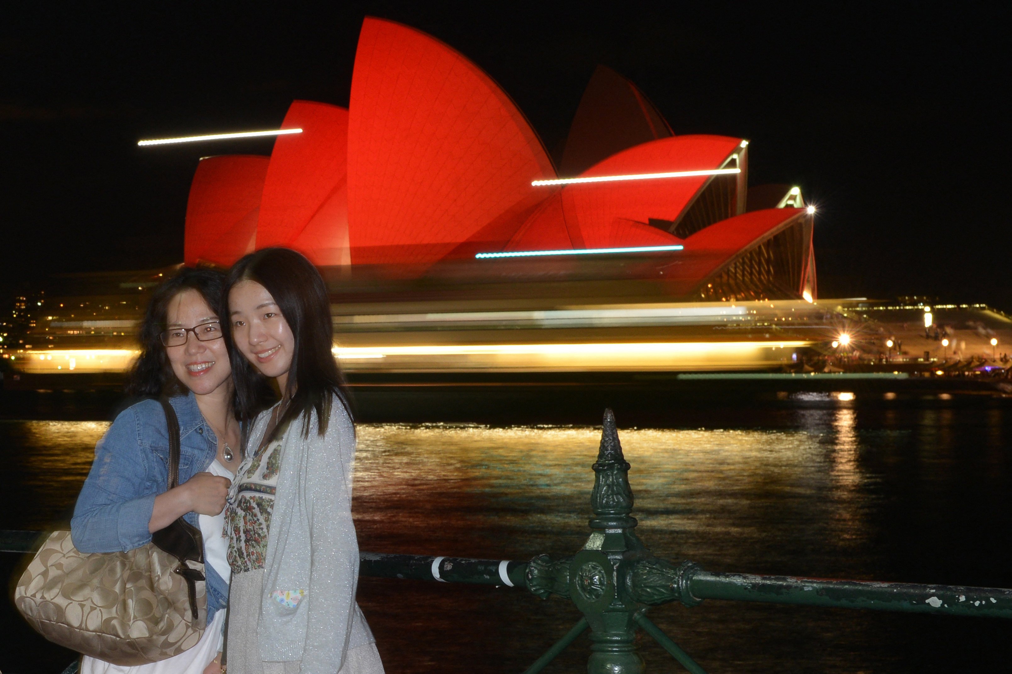 Chinese tourists take photos in front of the Sydney Opera House which is lit up red to welcome in the Lunar New Year in Sydney on February 8, 2016. Photo: AFP