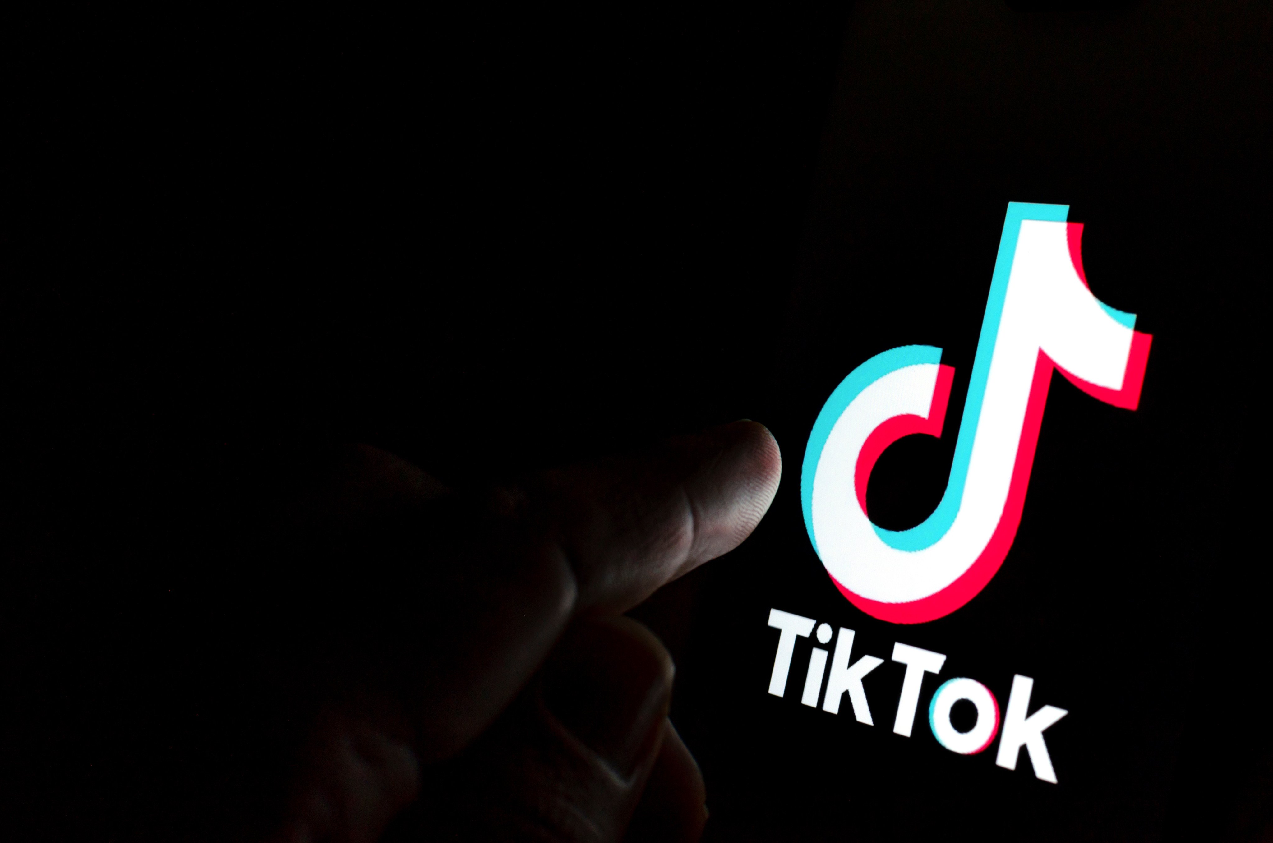 TikTok app logo on screen and a finger pointing at it.  Concept for app being in spotlight- blame, antitrust, regulation, child privacy, lawsuit, security. Stafford, United Kingdom - July 28 2019 Photo: Shutterstock Images
