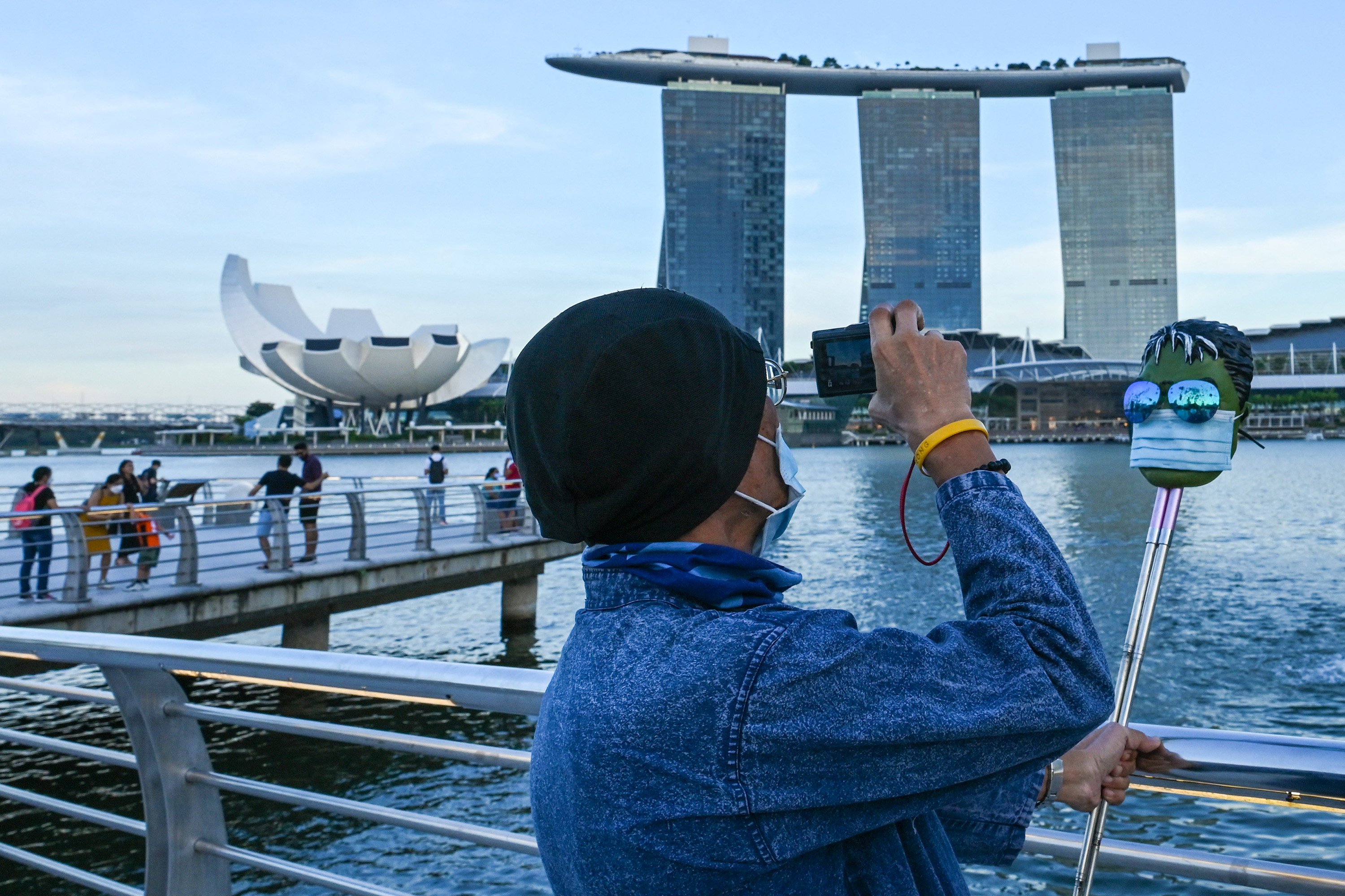 A man takes pictures of a mask wearing a face mask in front of the Marina Bay Sands hotel. The new wave accounts for more than two-thirds of infections in the city state. Photo: AFP