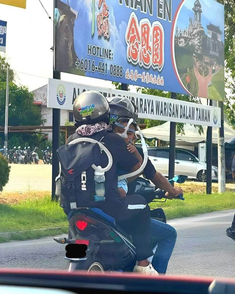 Norhidayu Halim holding her baby who is dependent on a breathing device on a motorcycle with Azlan Ishak. Photo: Facebook/ganu.pie
