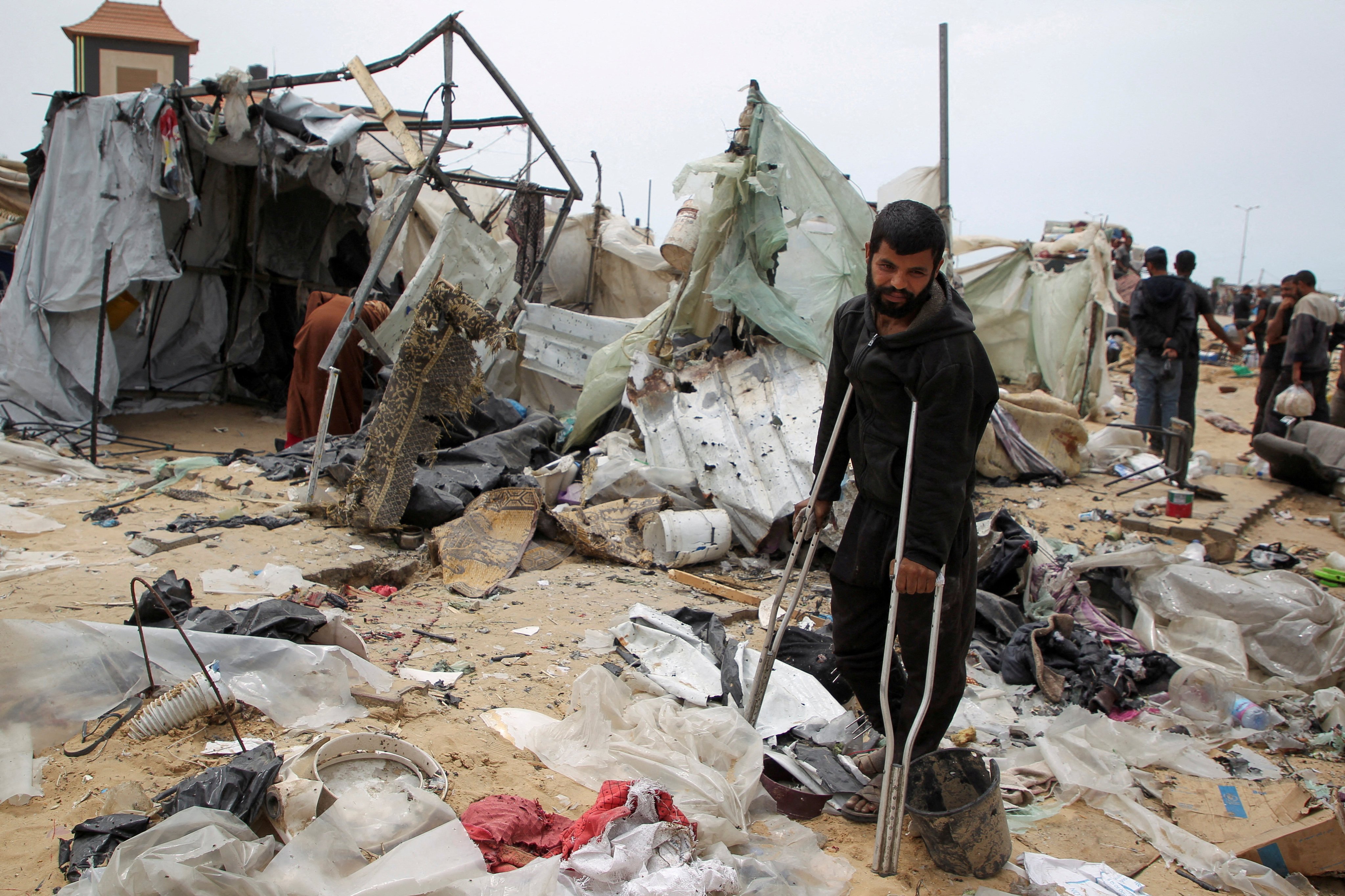 A man looks on as Palestinians on Tuesday inspect a tent camp damaged in an Israeli strike in Rafah. Photo: Reuters