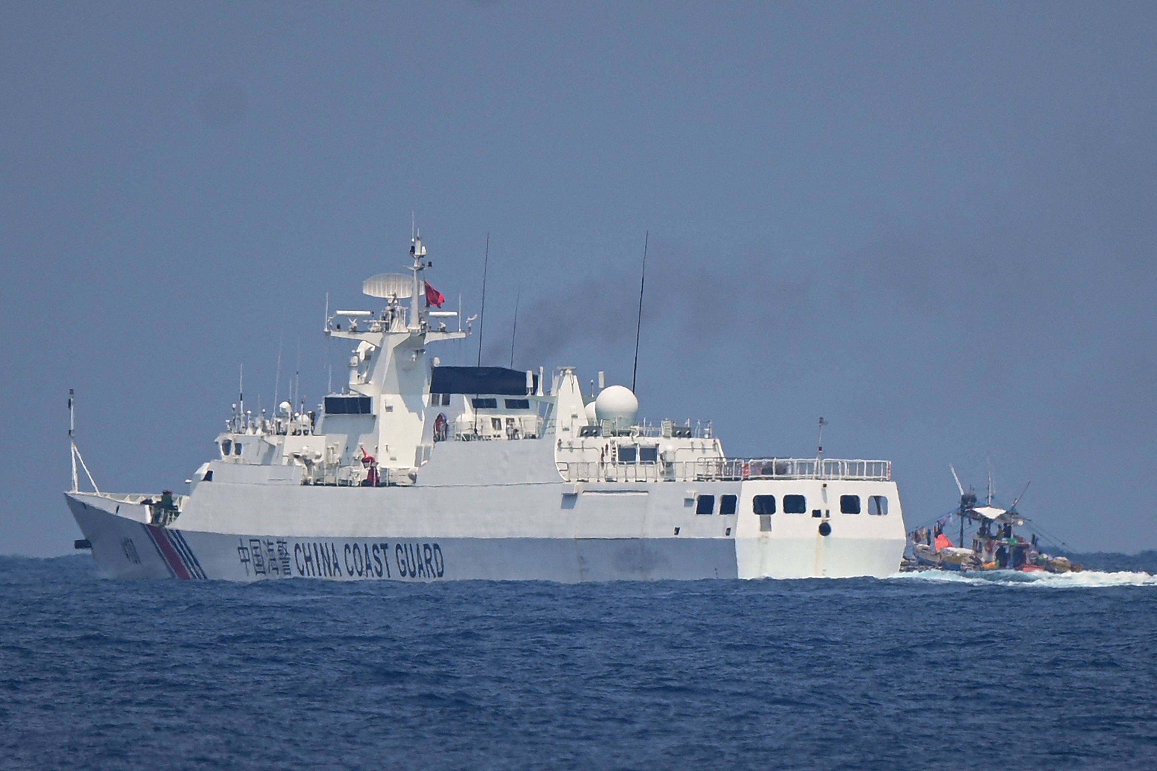 A Chinese coastguard ship sails past a Philippine fishing boat in the disputed South China Sea on May 16. Photo: AFP