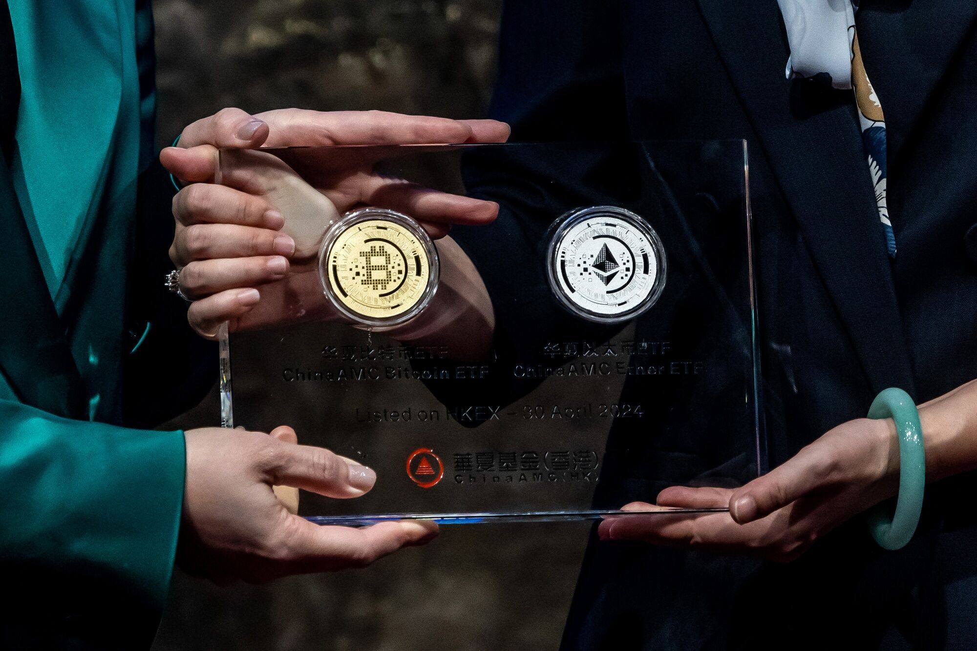 Illustrative bitcoin and ether tokens are held up during the listing ceremony of exchange-traded funds investing directly in cryptocurrency, at the Hong Kong Stock Exchange on April 30. Photo: Bloomberg