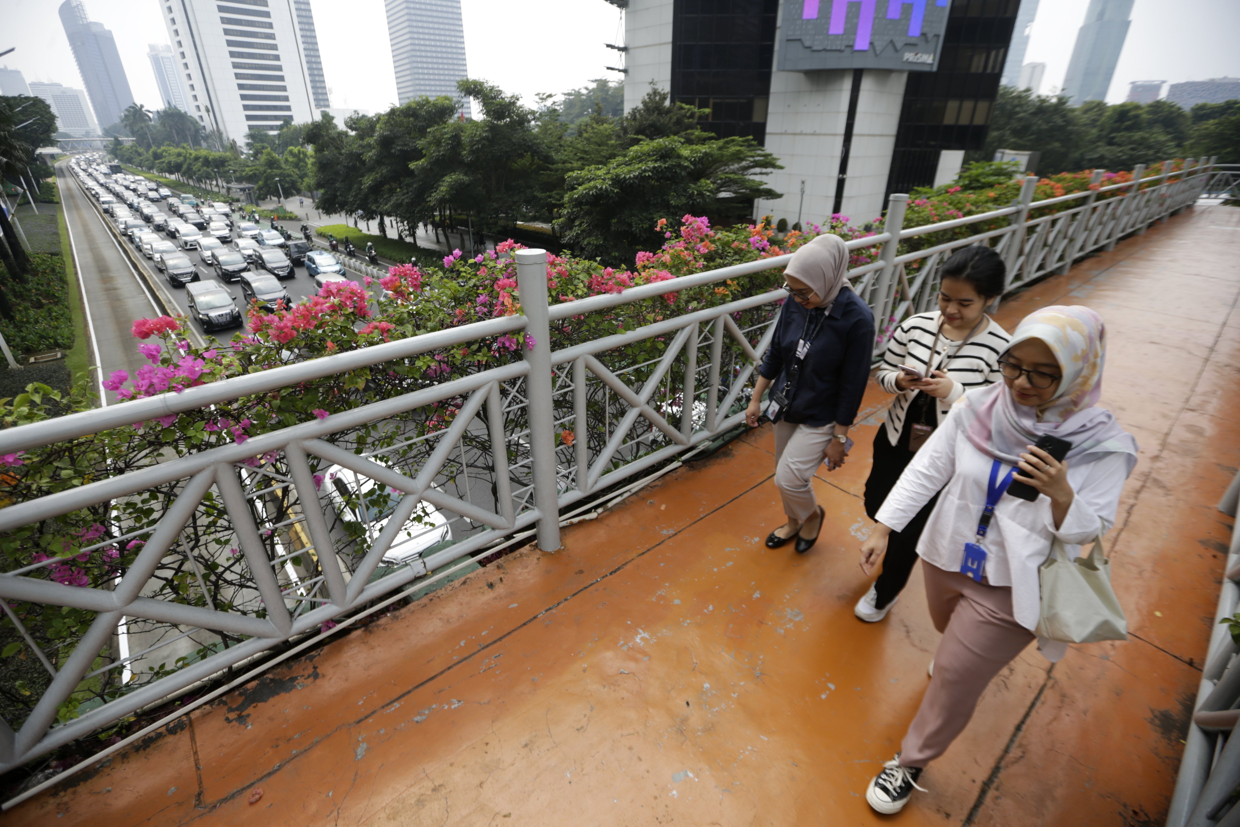 Indonesians walk on a pedestrian bridge in Jakarta on May 22. Workers are expected to contribute 3 per cent of their monthly income into a new savings fund starting next month. Photo: EPA-EFE