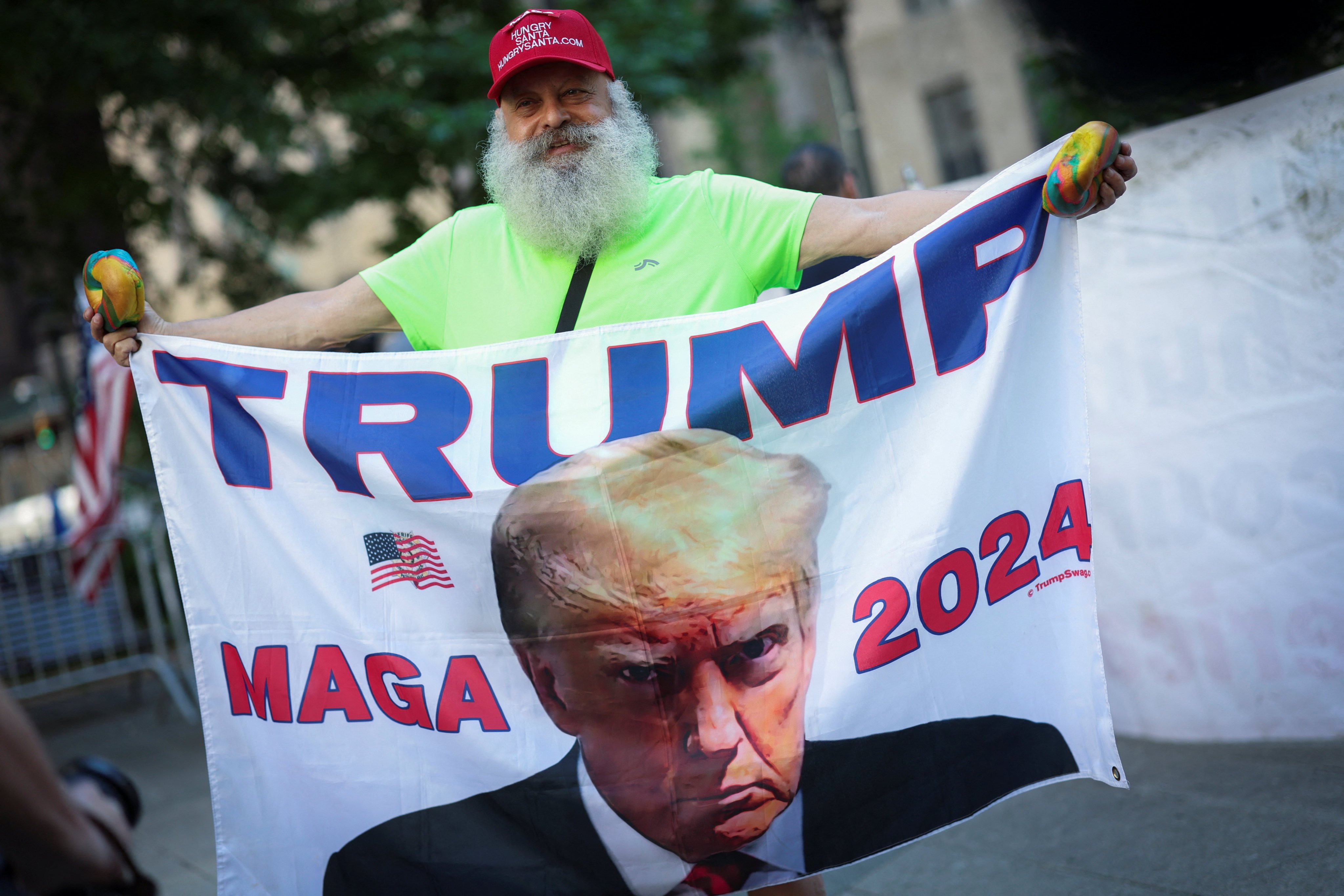 A Trump supporter holds a flag with the ex-US president’s image outside court in New York on Wednesday. Photo: Reuters