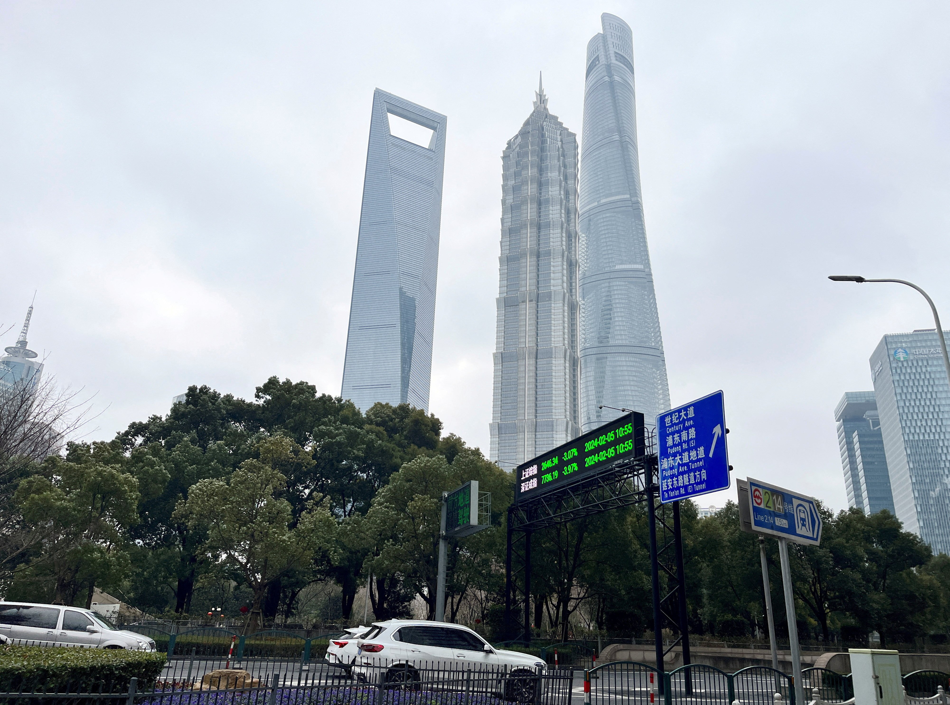 Cars travel past a display showing Shanghai and Shenzhen stock indexes near the Shanghai Tower and other skyscrapers at the Lujiazui financial district in Shanghai on February 5, 2024. Photo: Reuters