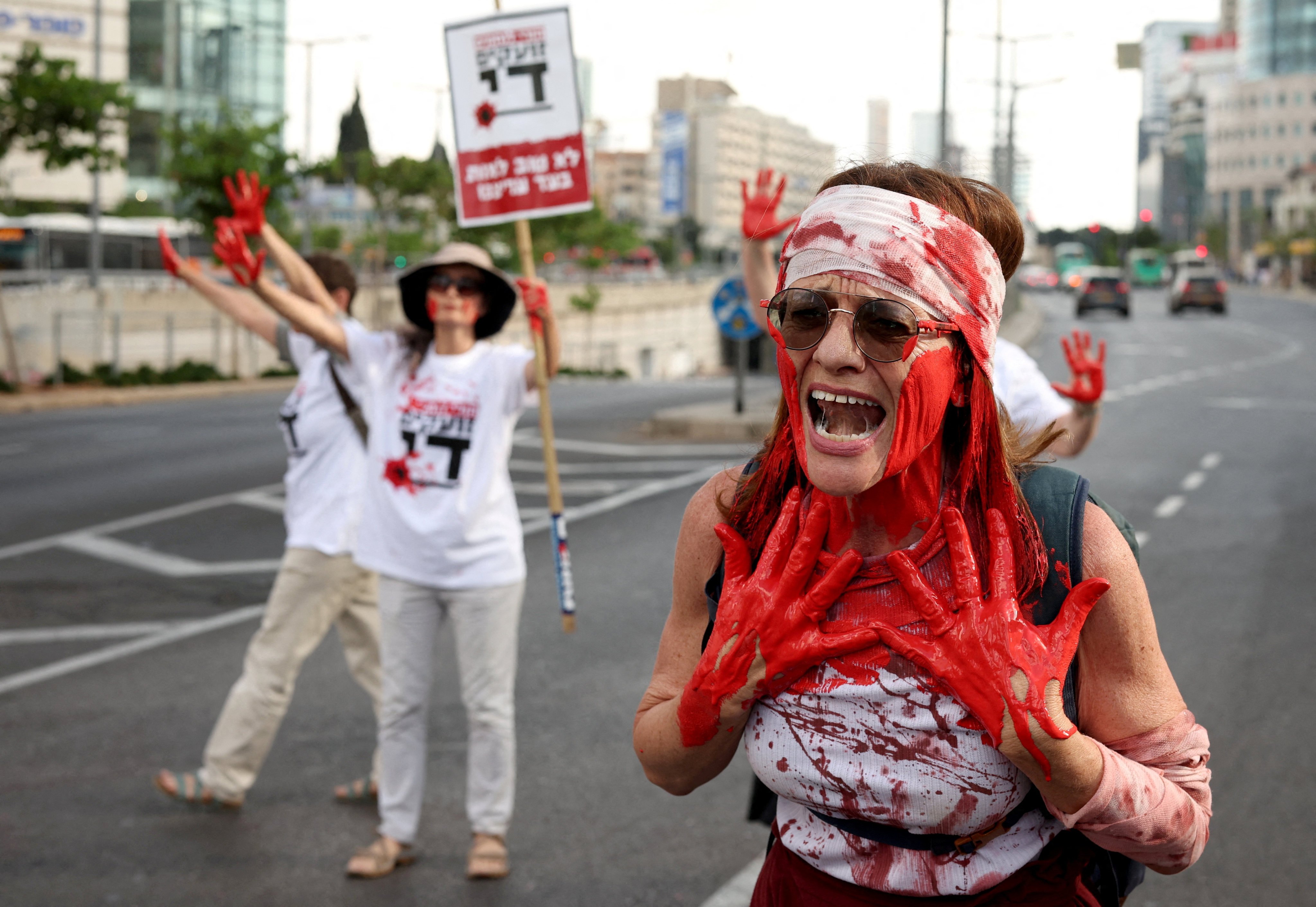 Covered in red paint, mothers of Israeli soldiers serving in the Gaza Strip block a road in Tel Aviv on Wednesday to demand an end to the ongoing conflict. Photo: Reuters