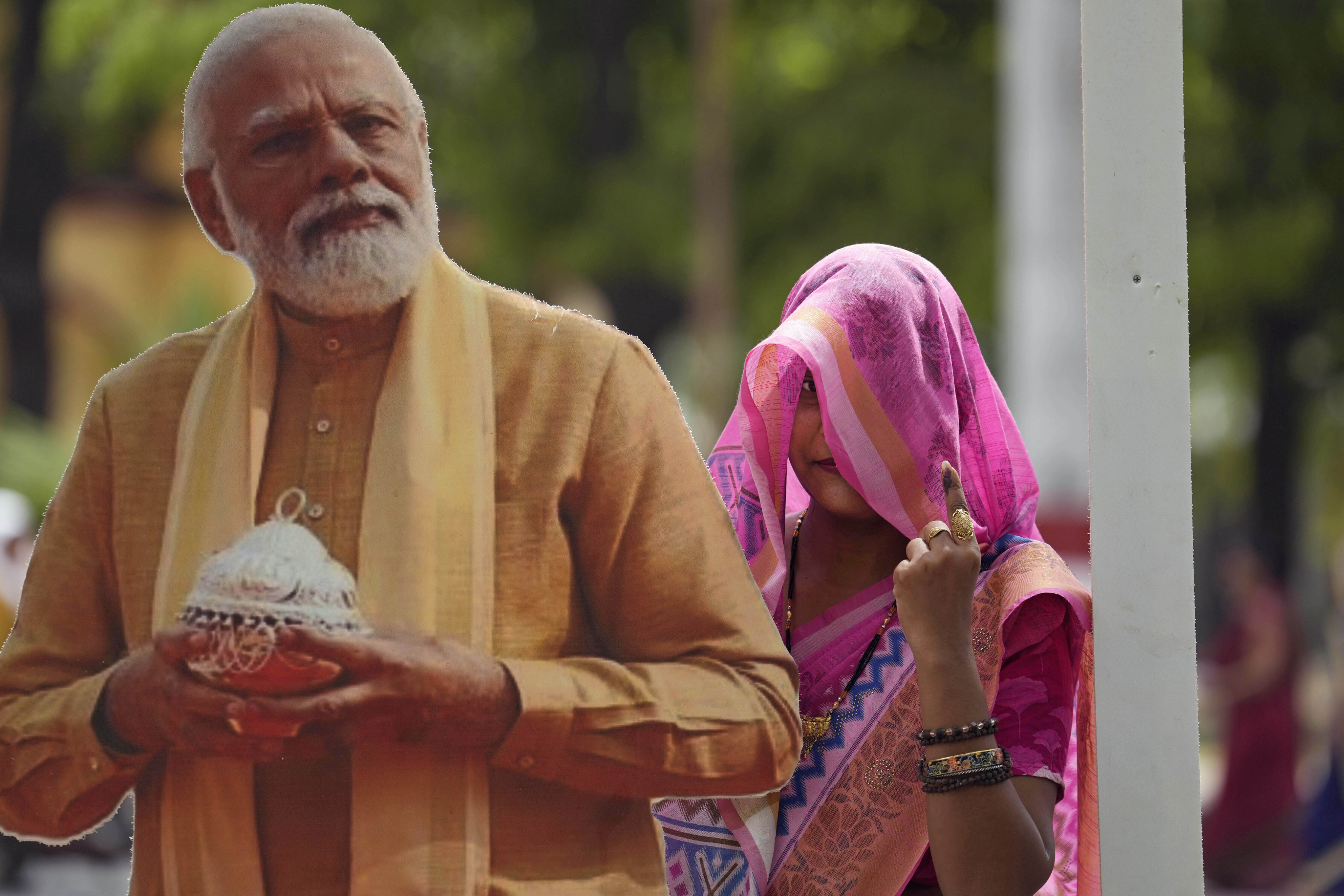 A woman shows her index finger marked with an indelible ink as she poses for a photograph next to a cut-out portrait of Indian Prime Minister Narendra Modi after voting in Varanasi, India, on Saturday. Photo: AP