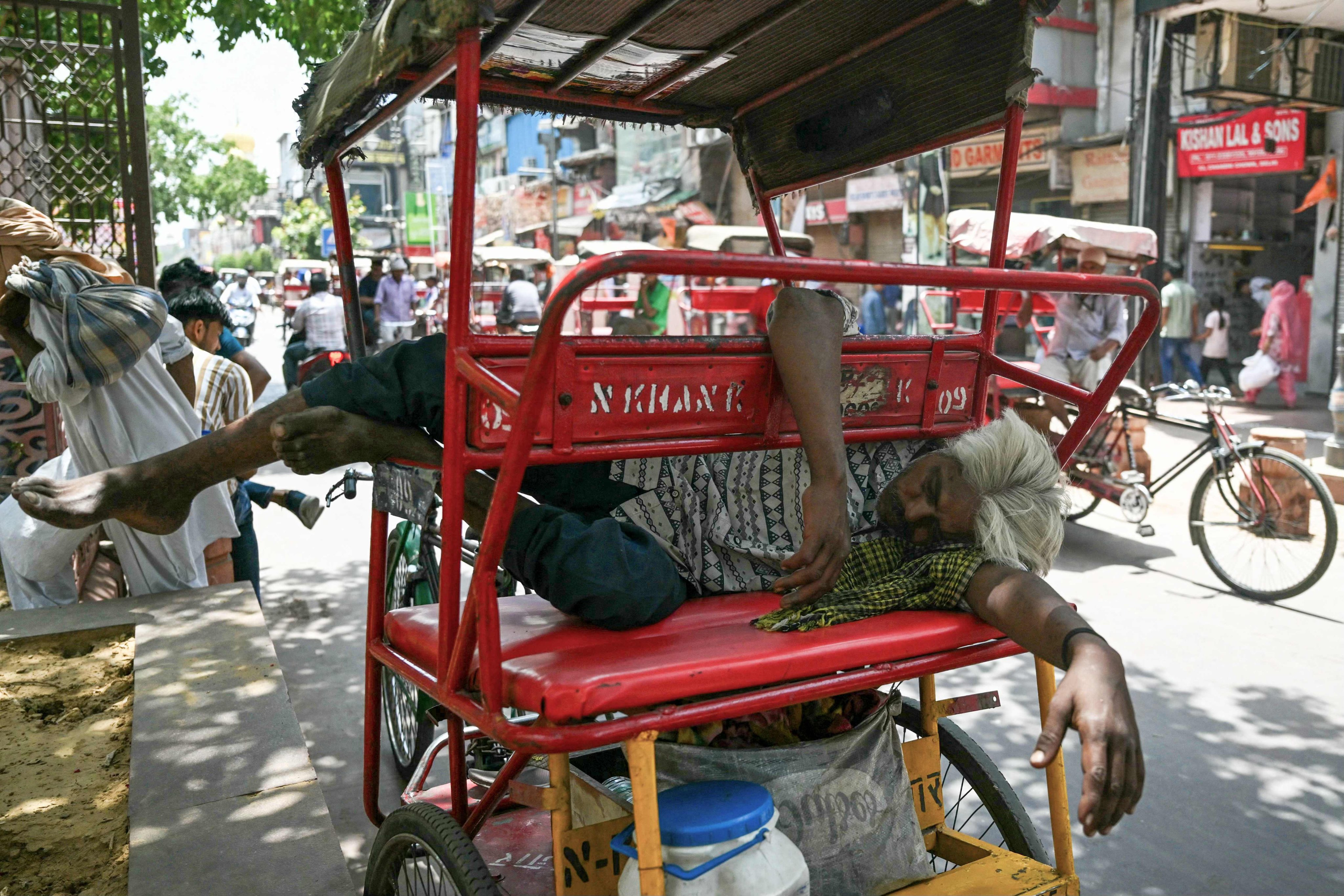 A man sleeps on his rickshaw along a street on a hot summer day in New Delhi on May 31. Photo: AFP