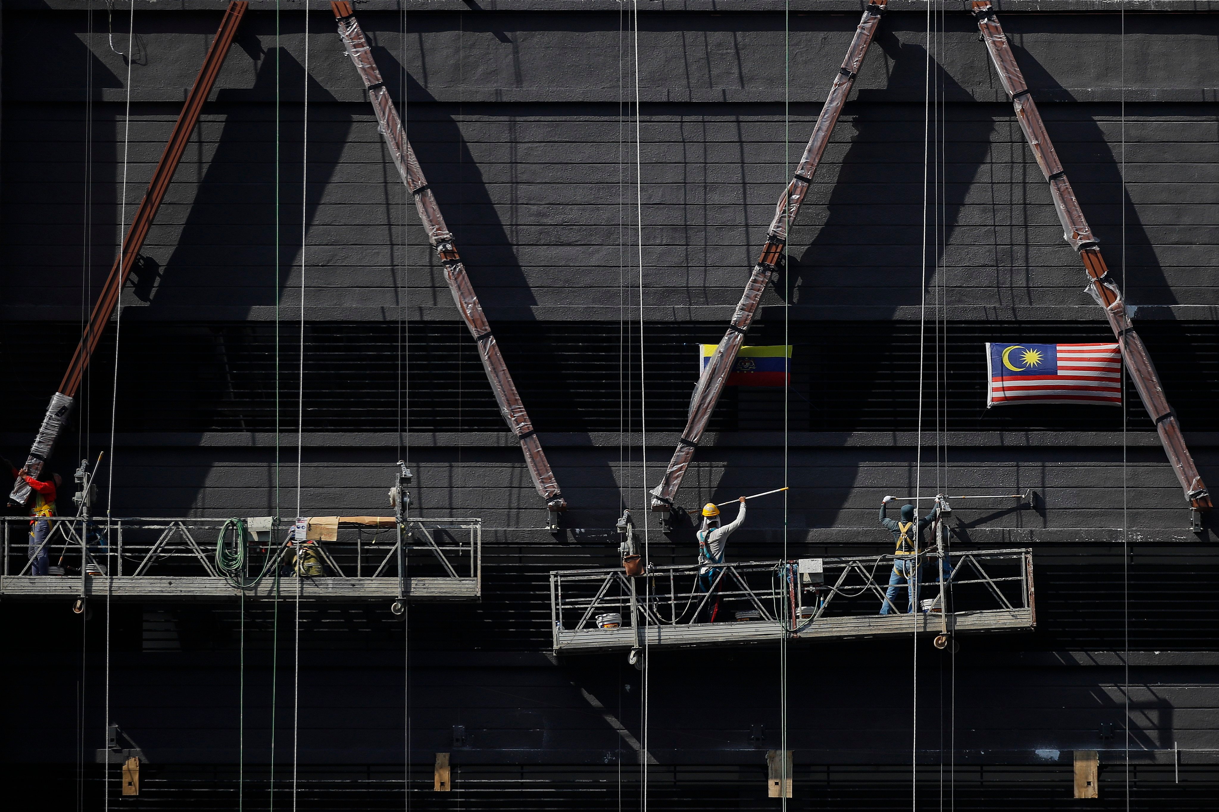 Construction workers paint a building in Kuala Lumpur. Malaysia has been in the spotlight for months over allegations that forced labour, debt bondage and scam jobs have riddled its recruitment market for foreign labour. Photo: EPA-EFE