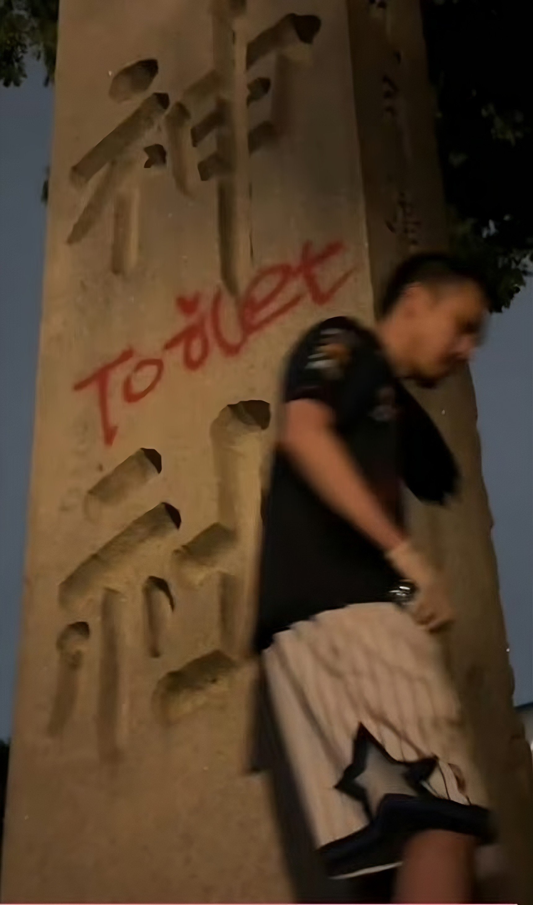 A still from a video that circulated on Chinese social media shows an unidentified man next to the word “toilet” in red graffiti on a pillar at Tokyo’s Yasukuni. Photo: X/Ek_aike