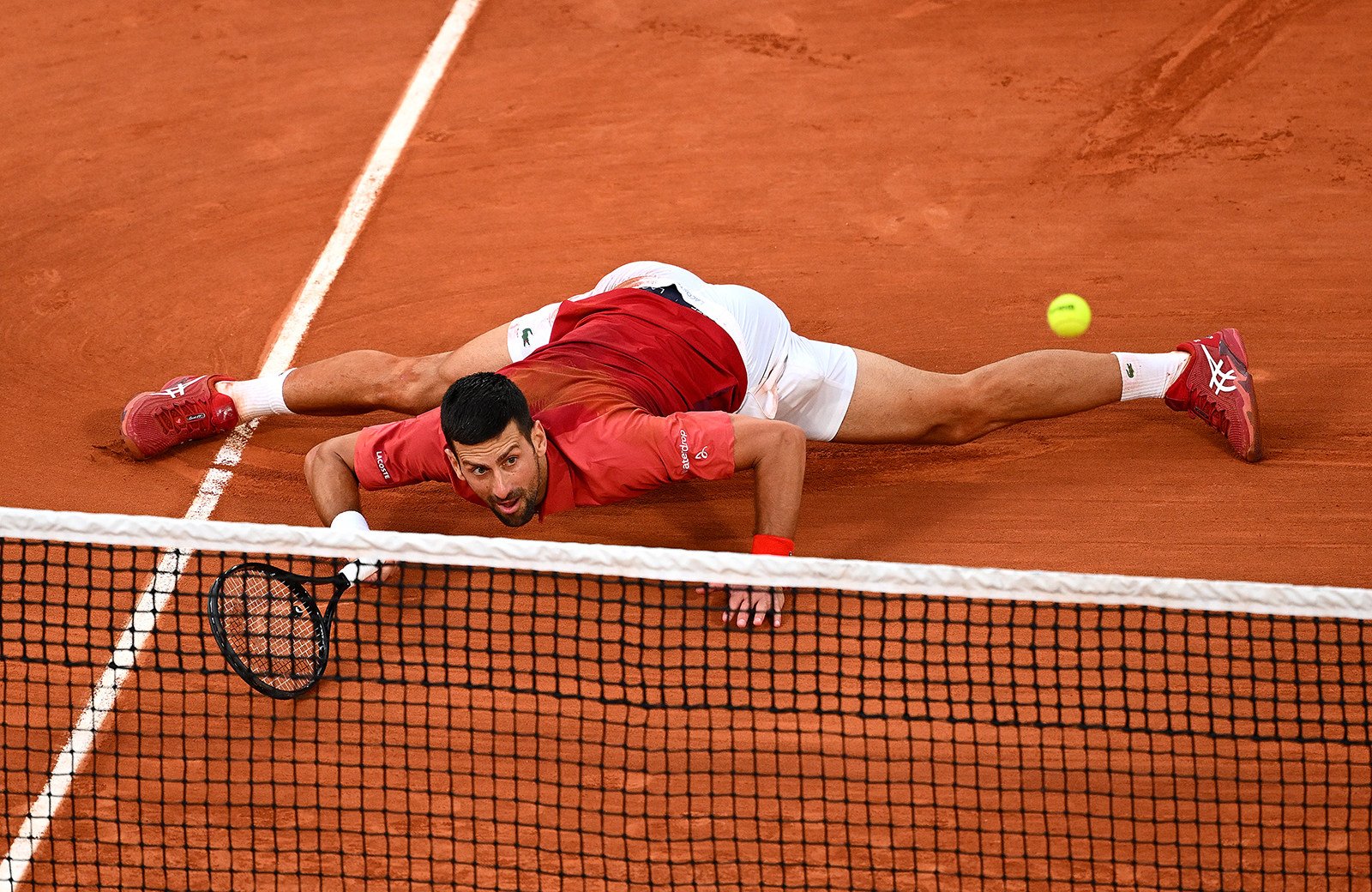 Novak Djokovic slides at the net for a forehand against Francisco Cerundolo during their men’s singles fourth round match at the French Open. Photo: Getty Images