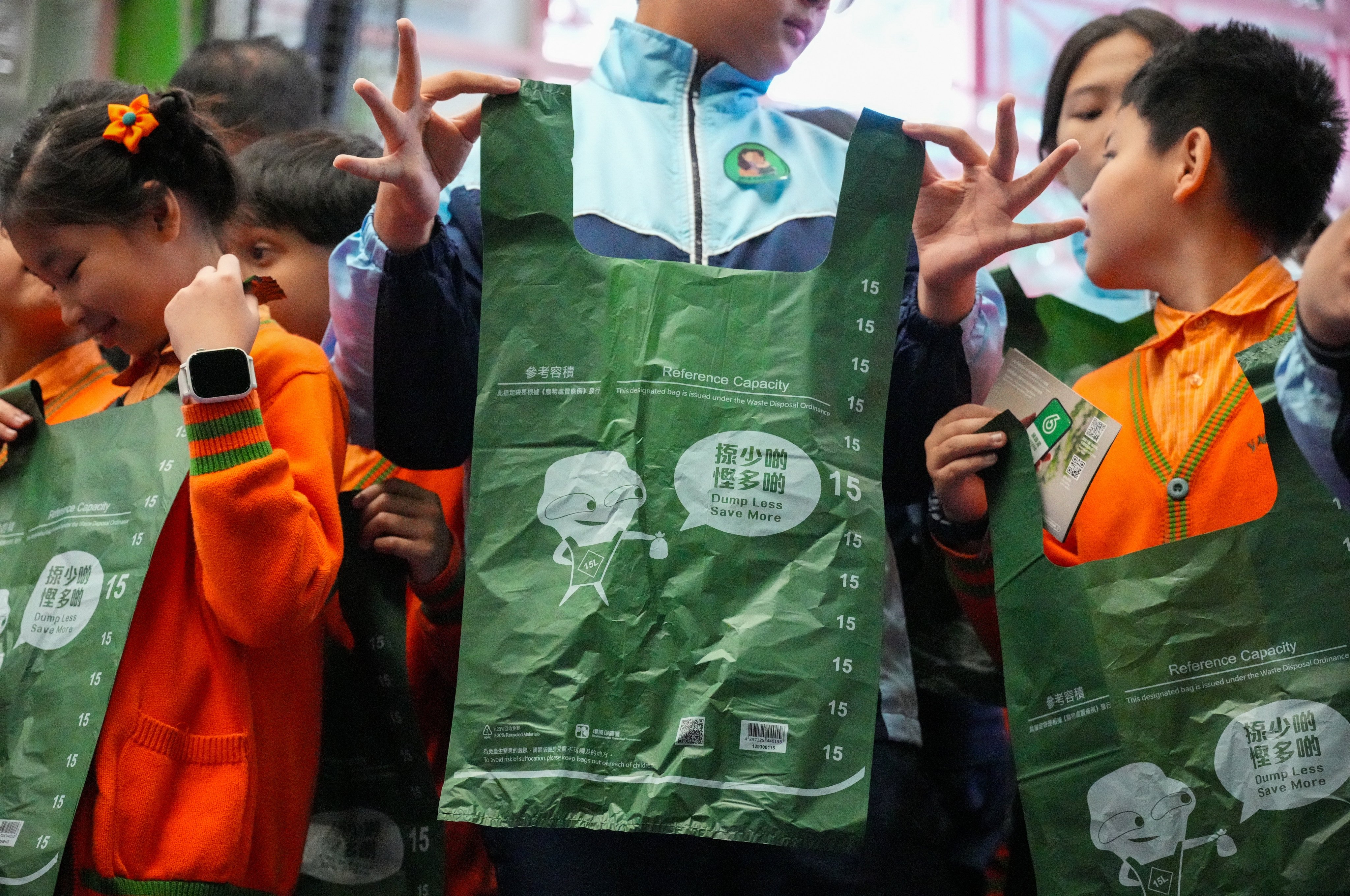 Students hold up designated bags for the waste-charging scheme during a promotional event on January 16. The scheme has been shelved, and the government has pledged to hand out 20 bags for free to every household in public rental flats monthly for half a year. Photo: Eugene Lee 
