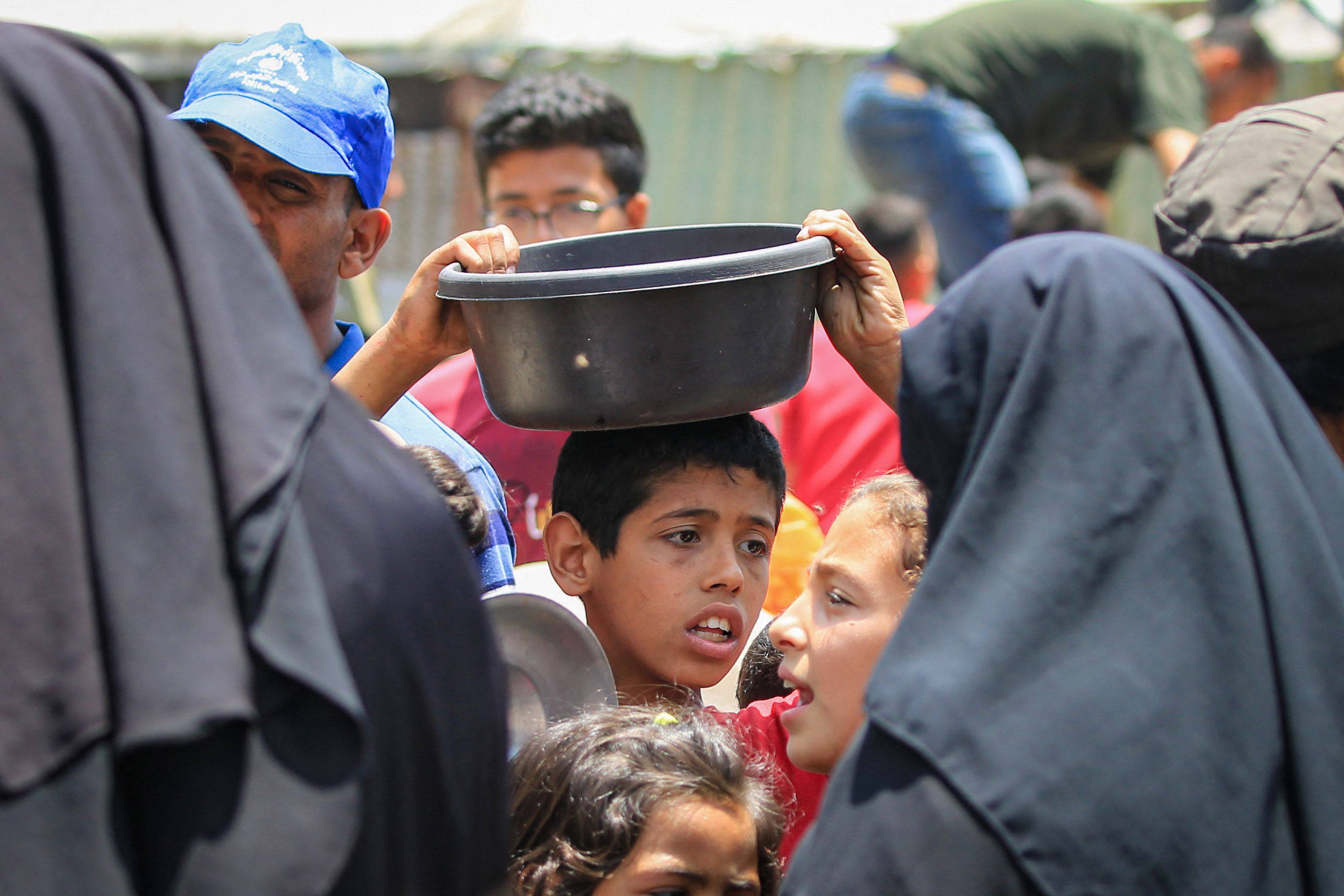 Palestinians queue for meal rations at a communal food distribution point in al-Bureij refugee camp in the besieged Gaza Strip. Photo: AFP