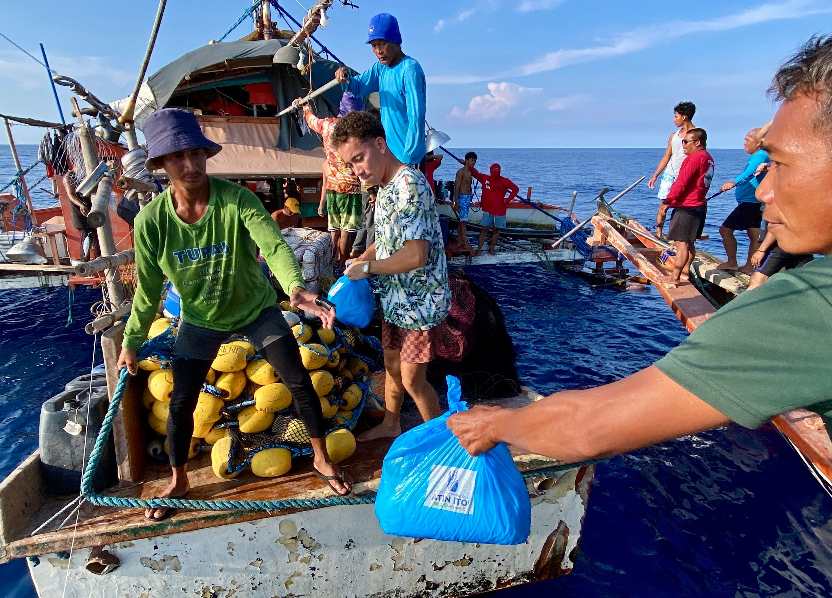 Filipino volunteers from the civilian-led relief mission Atin Ito (It’s Ours!) group distribute relief goods to fishermen aboard a motorised wooden boat on the waters of the disputed South China Sea, on May 16. Photo: EPA-EFE