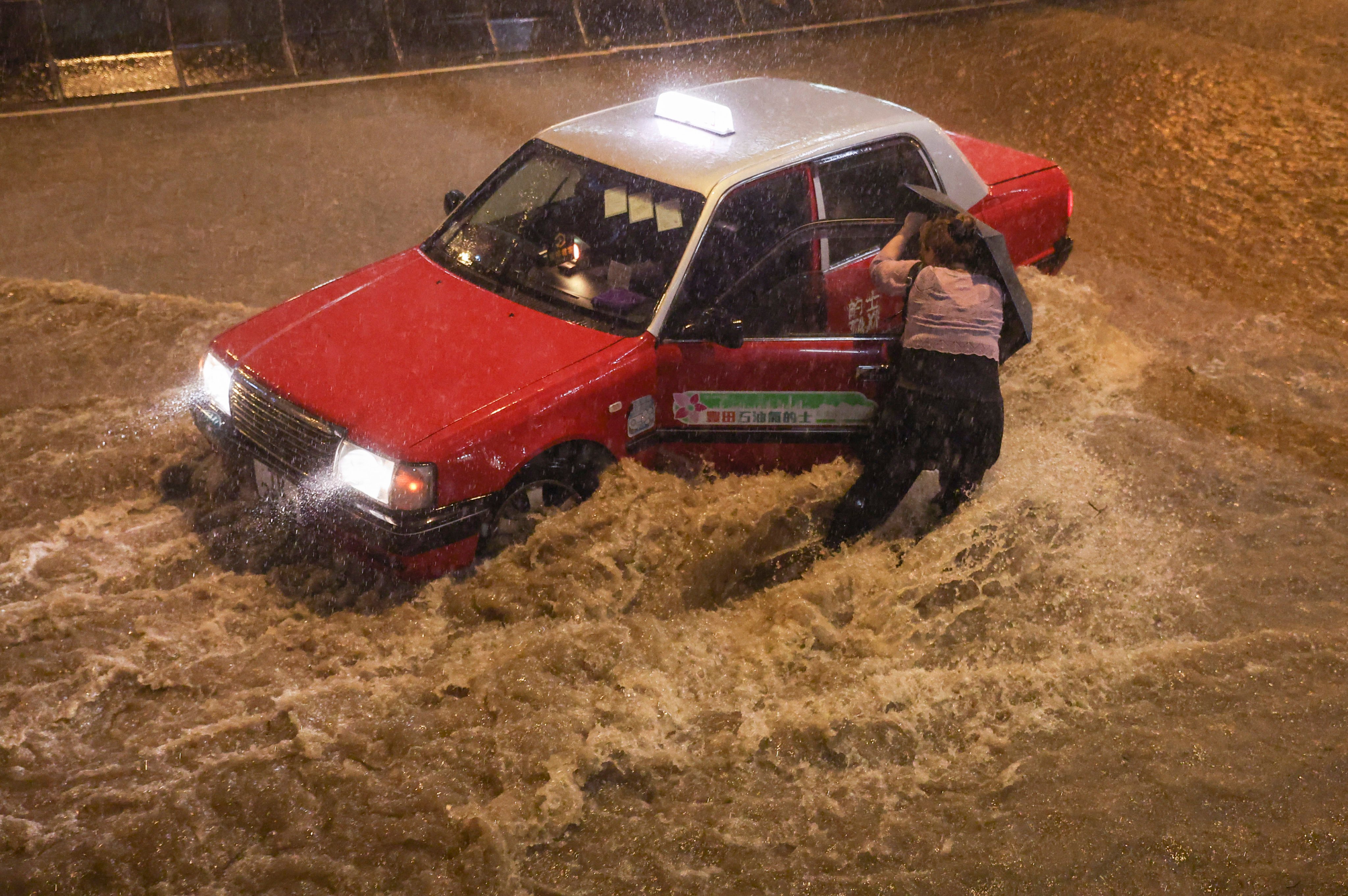 A woman tries to get into a taxi in Choi Hung during the black rainstorm warning on September 8. Frequent complaints about taxi drivers are surely insignificant against the millions of safe miles Hong Kong taxis drive to keep the wheels of the economy turning. Photo: Edmond So
