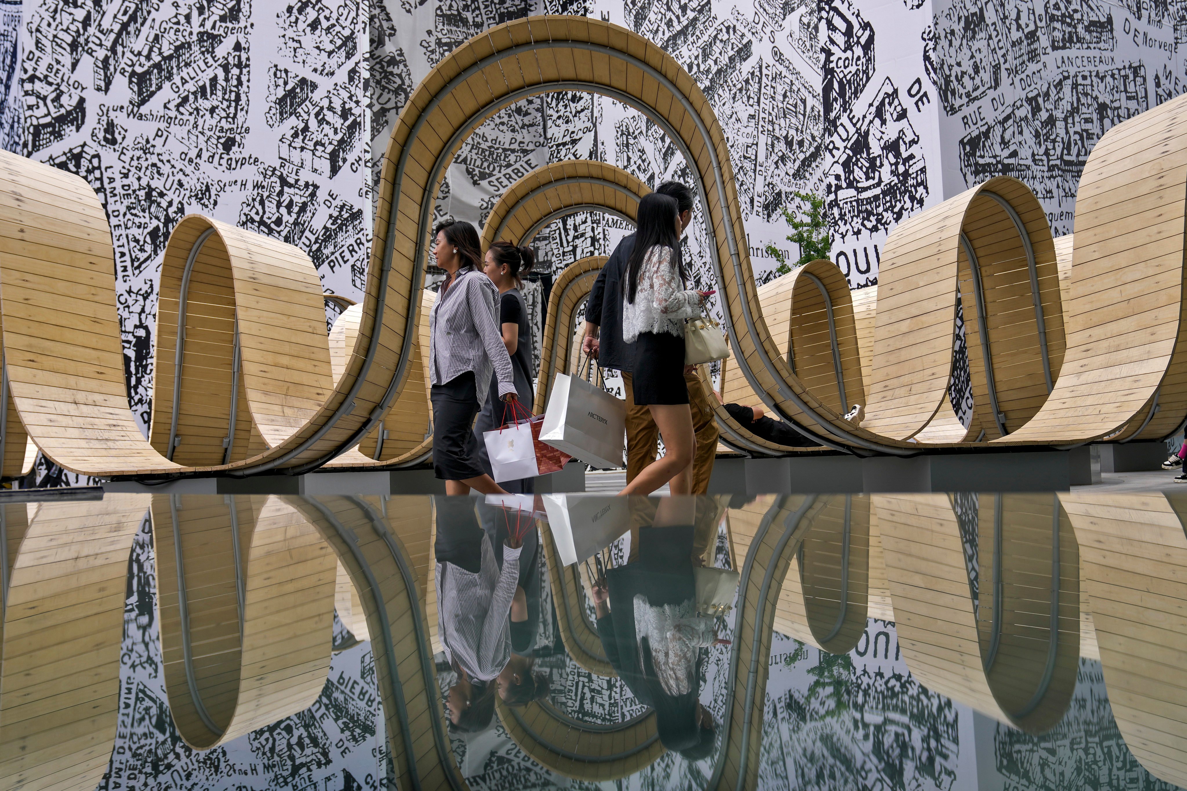 Shoppers walk by a reflected art installation at an outdoor luxury shopping mall in Beijing on June 5. Local companies will need to learn how to build truly global companies, stop depending on “one-hit wonders” and start really understanding their customers.  Photo: AP