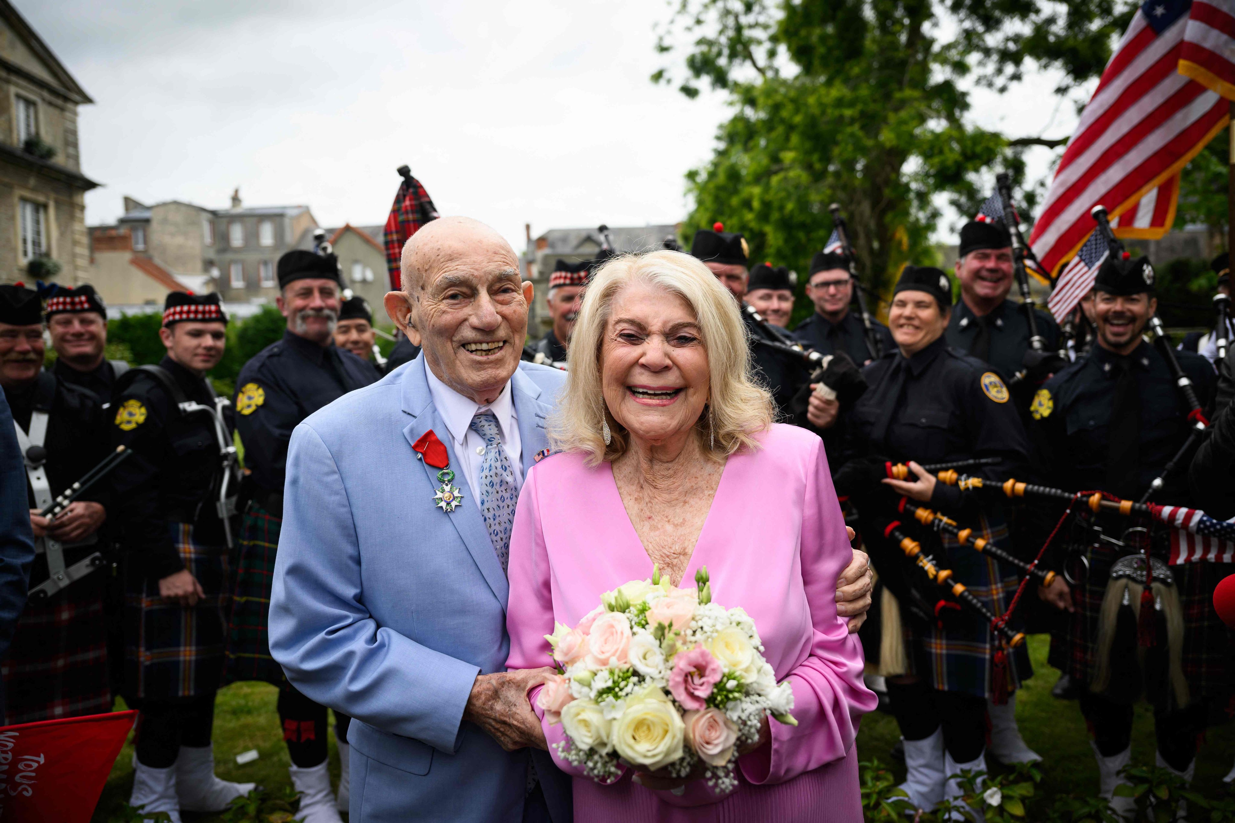 Newlyweds Jeanne Swerlin and US WWII veteran Harold Terens pose for photographs in front of a piper band as they celebrate their marriage during a wedding at the town hall of Carentan-les-Marais, in Normandy, northwestern France, on Saturday. Photo: AFP