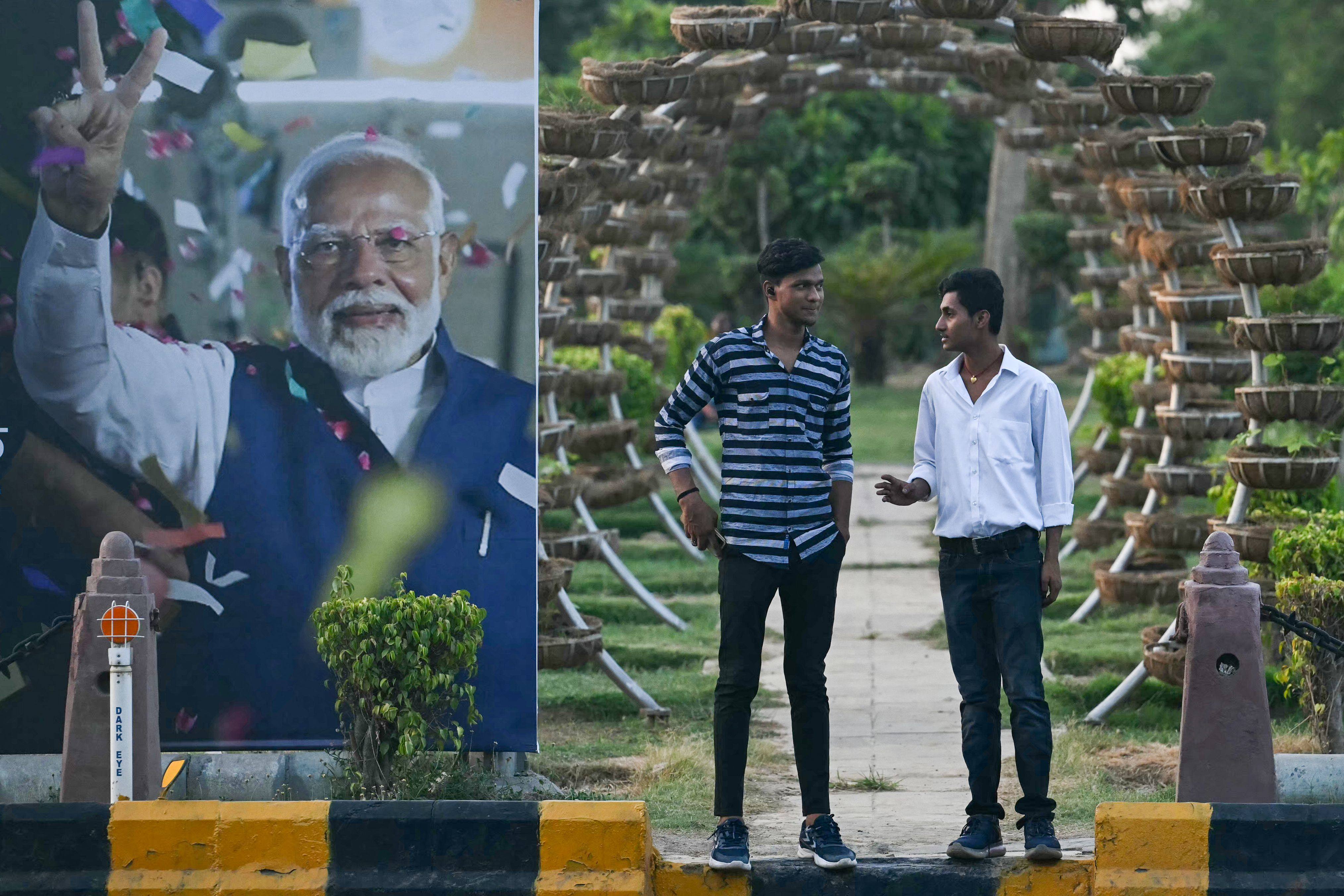 Pedestrians stand along a road next to a billboard displaying an image of India’s leader Narendra Modi on the day of his oath-taking ceremony, in New Delhi. Photo: AFP