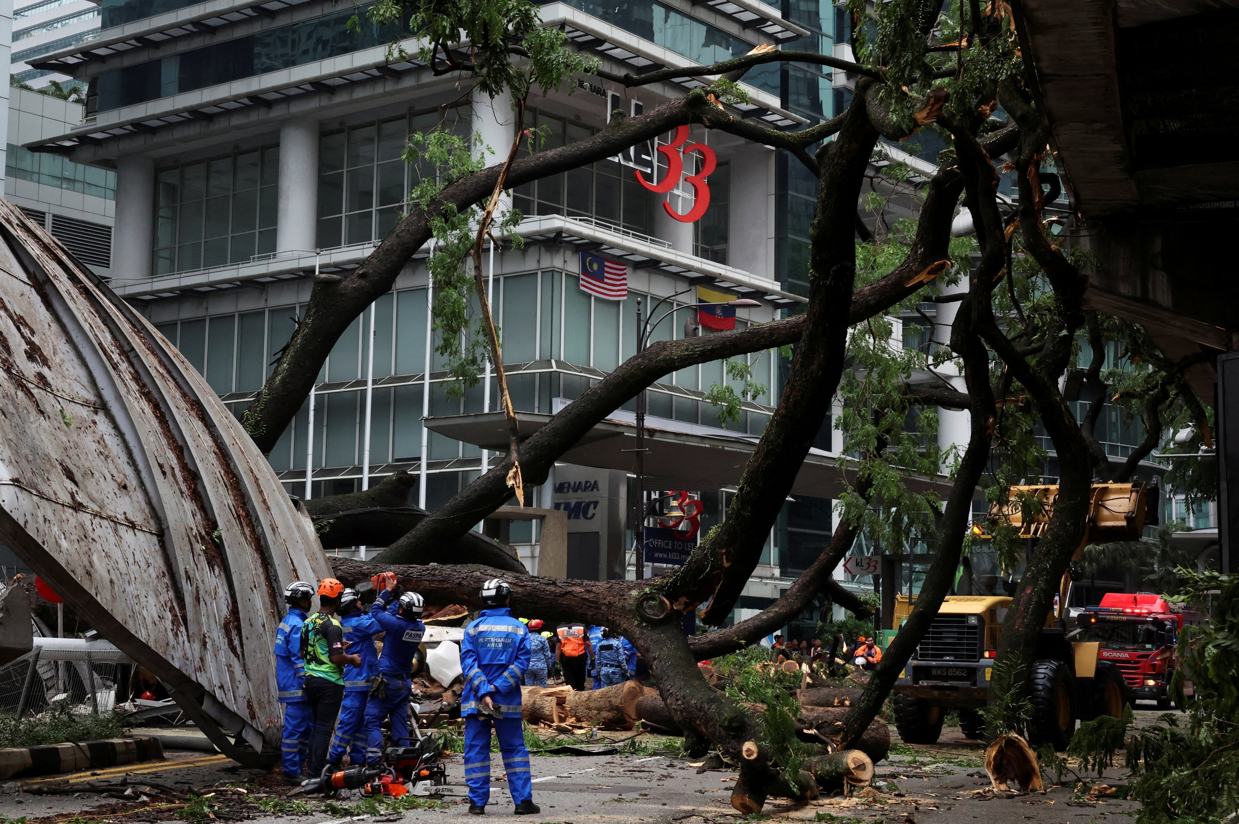 Rescuers stand where a tree fell across one of Kuala Lumpur’s busiest roads on May 7, killing a motorist. Photo: Reuters