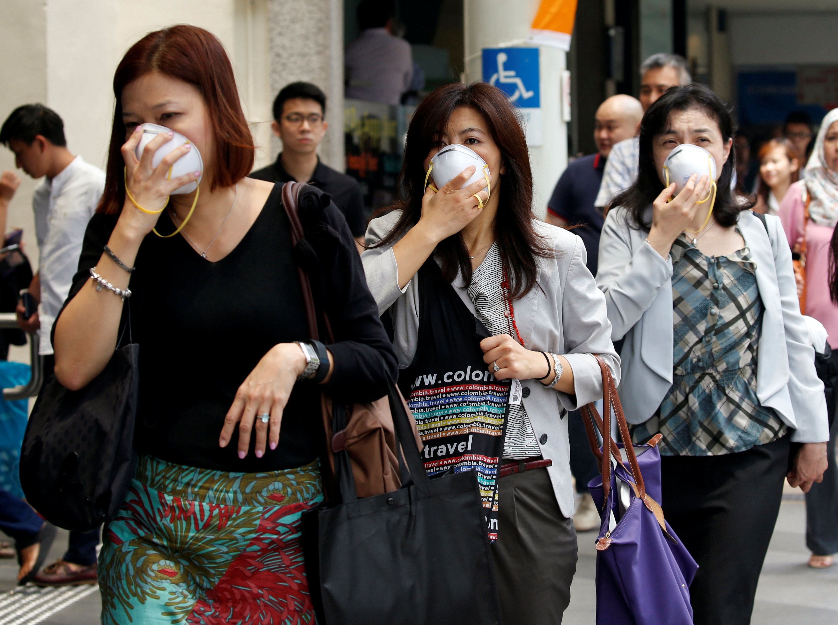 Women cover their faces with masks as haze shrouds Singapore’s central business district in 2016. Photo: Reuters
