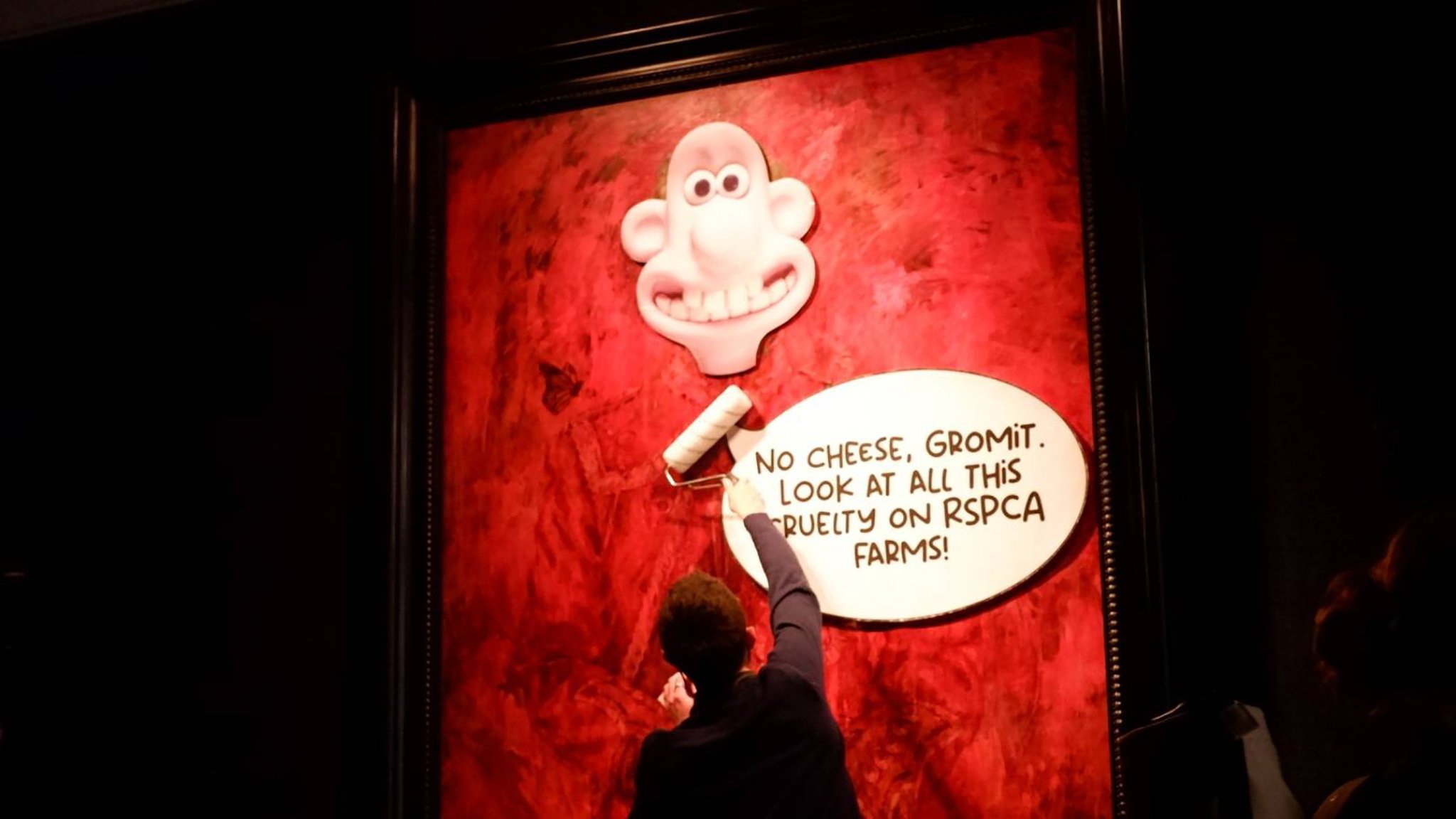 An activist puts the face of animated character Wallace over the painting of King Charles at the Philip Mould gallery in London on Tuesday. Photo: Animal Rising via EPA-EFE