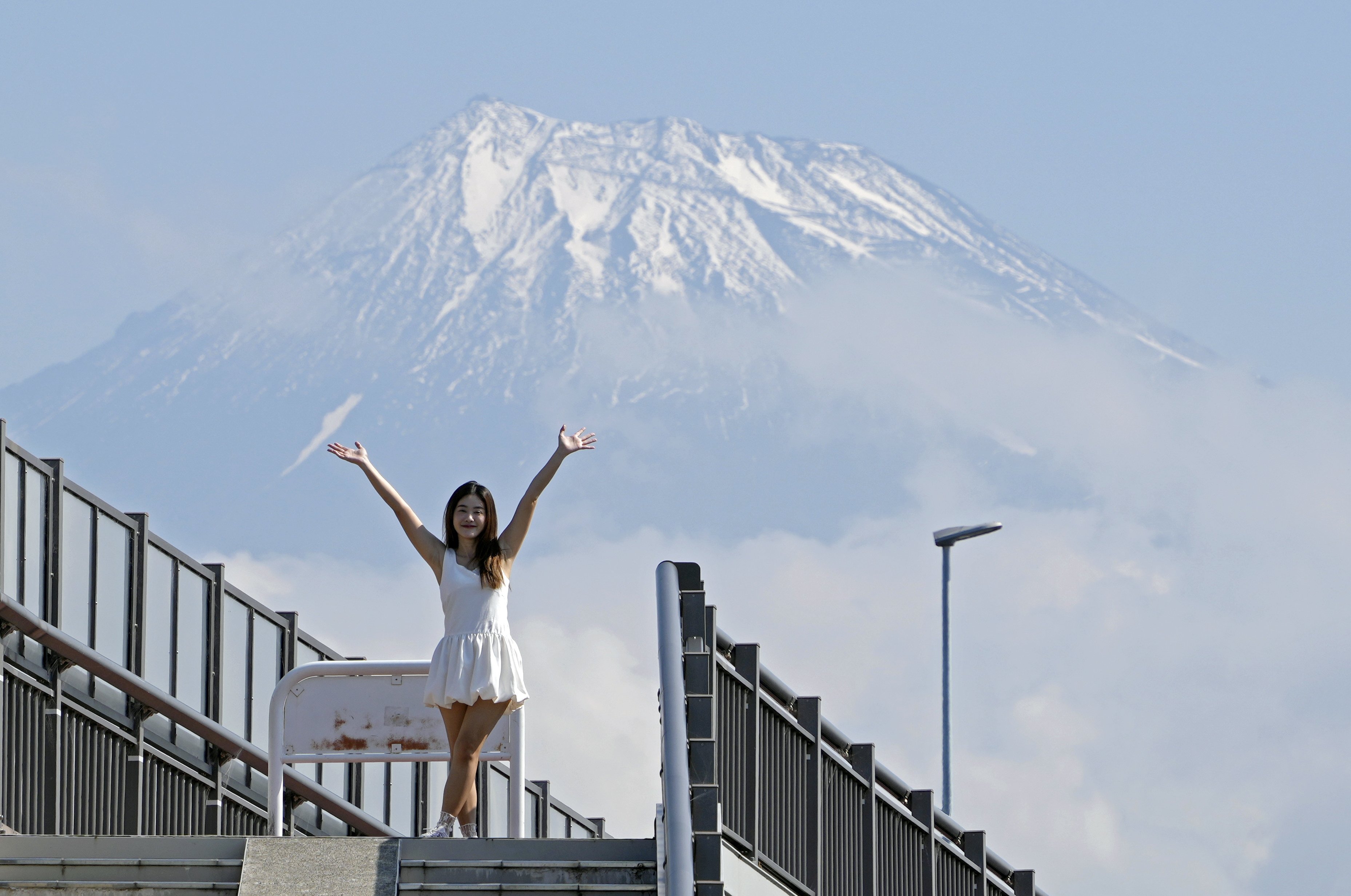 A tourist from Thailand poses on the Mount Fuji Dream Bridge in Fuji City, where authorities plan to erect a fence to stop visitors blocking the road to snap their dream photo. Photo: EPA-EFE
