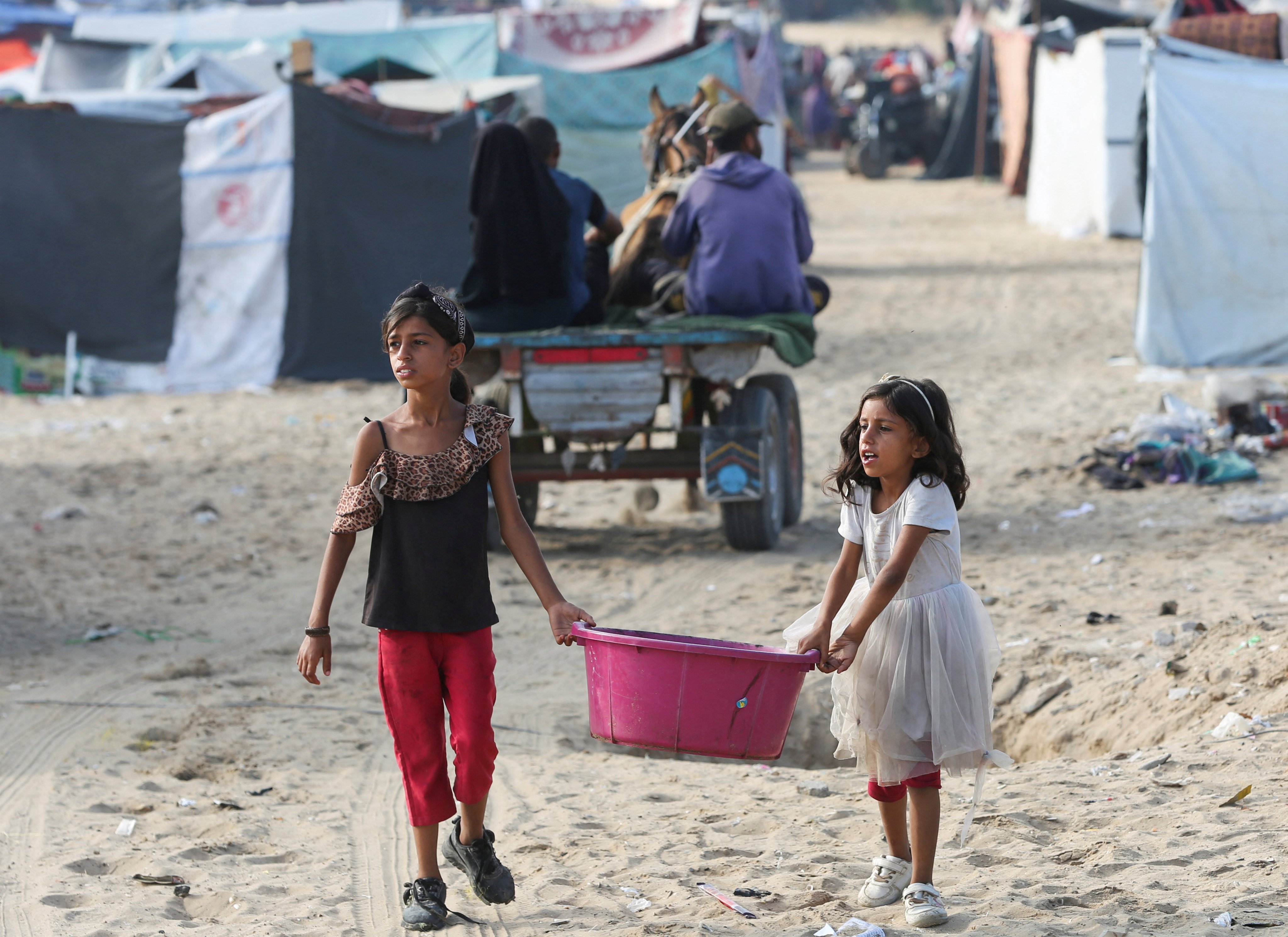 Girls walk carrying a container as Palestinians flee Rafah due to an Israeli military operation. Photo: Reuters