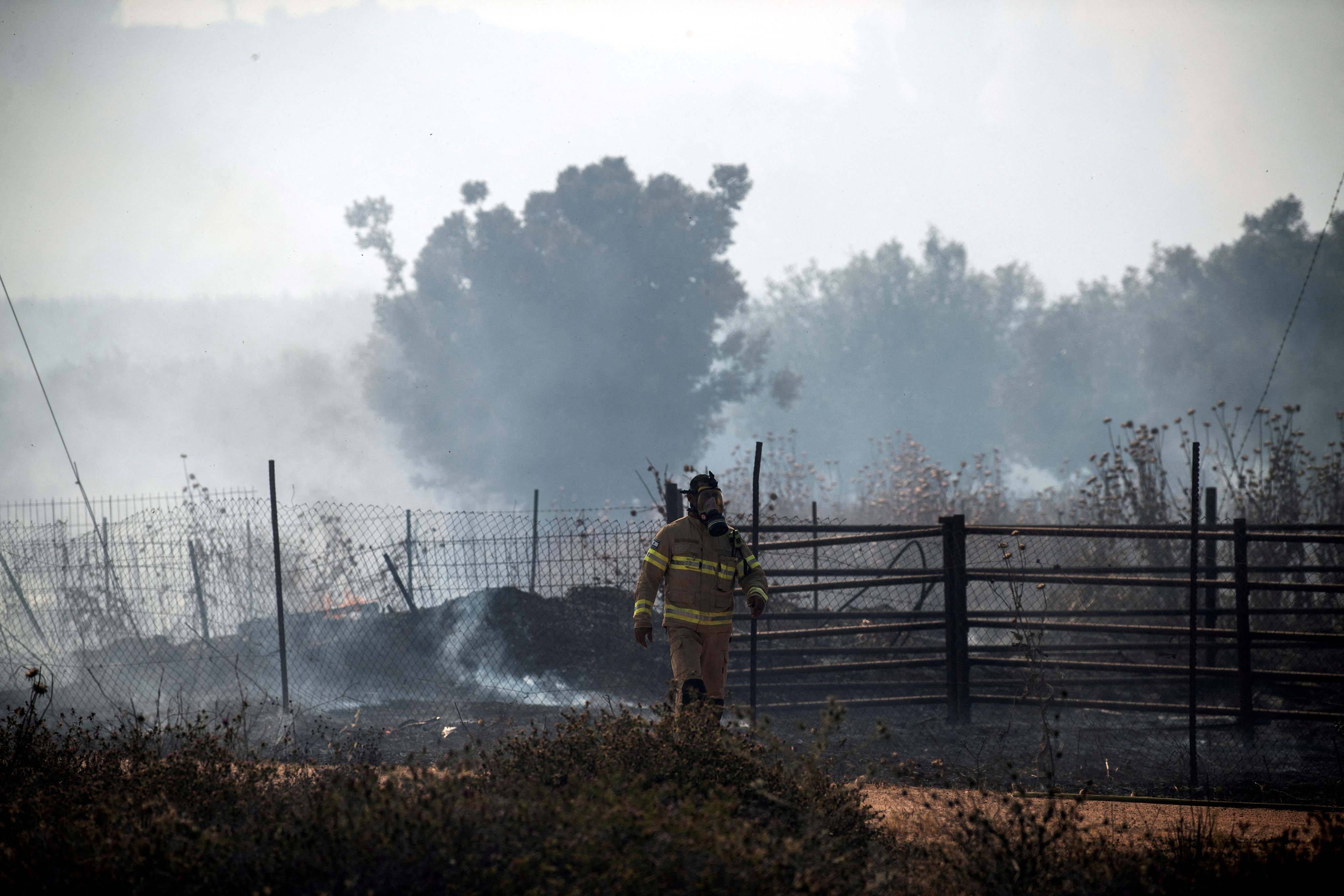 An Israeli firefighter is seen in the smoke from fires that started in a rocket attack launched from Lebanon into northern Israel on Wednesday. Photo: Reuters