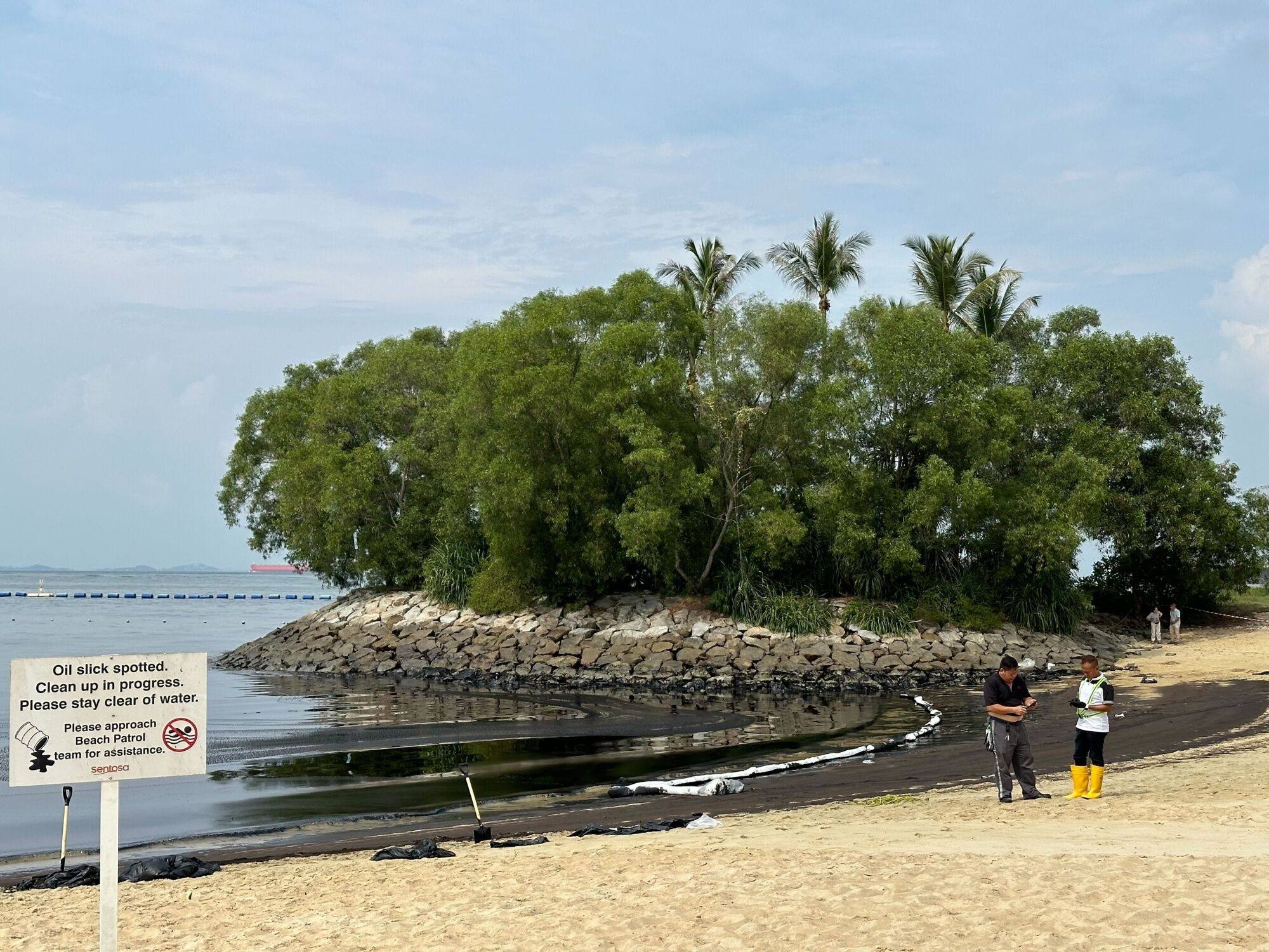 Clean-up crew next to oil-coated sand and rocks along the Tanjong Beach on Sentosa island in Singapore on June 15. Photo: Bloomberg