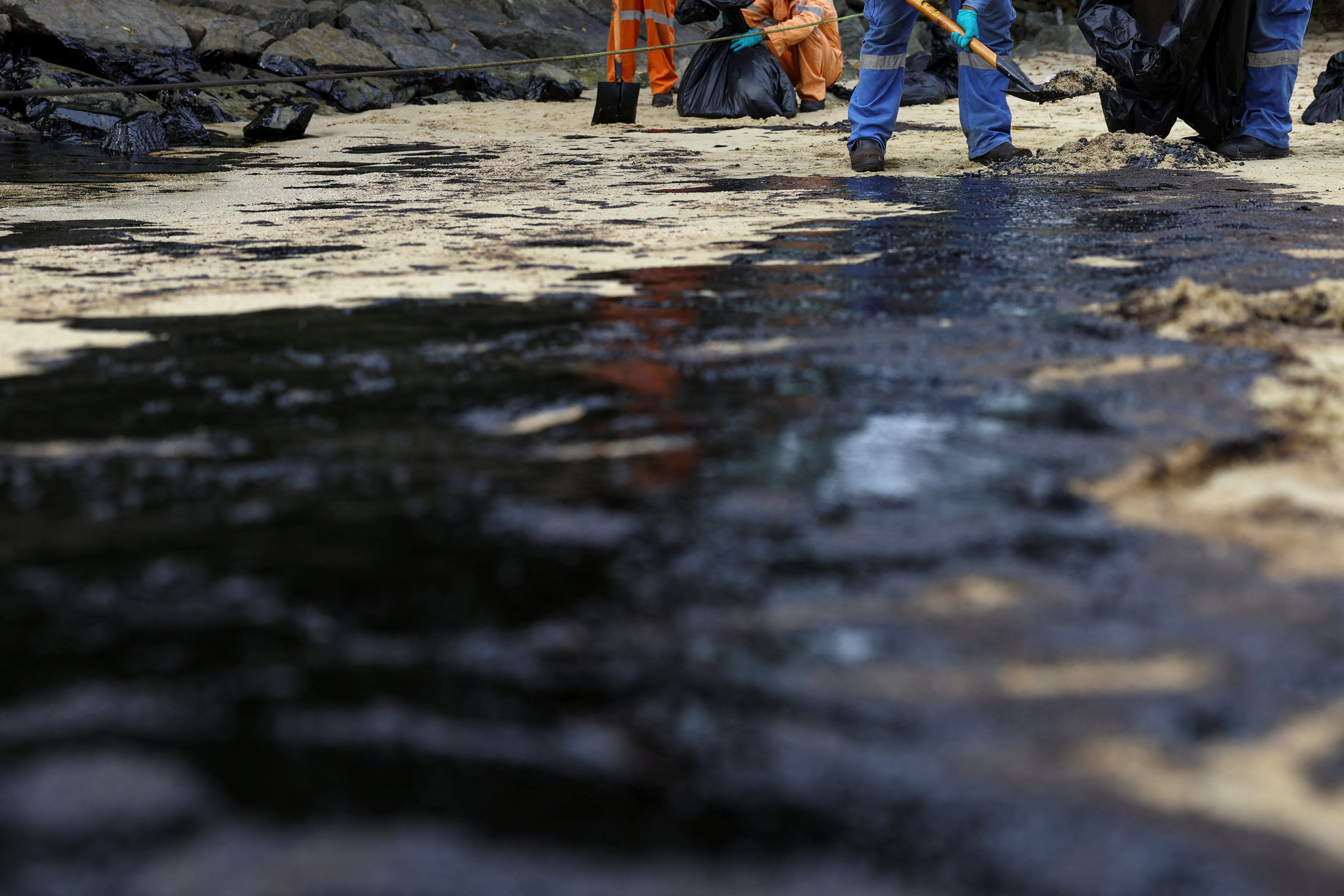Workers clean up the oil slick on Sentosa Island’s Tanjong Beach in Singapore on Sunday. Photo: Reuters