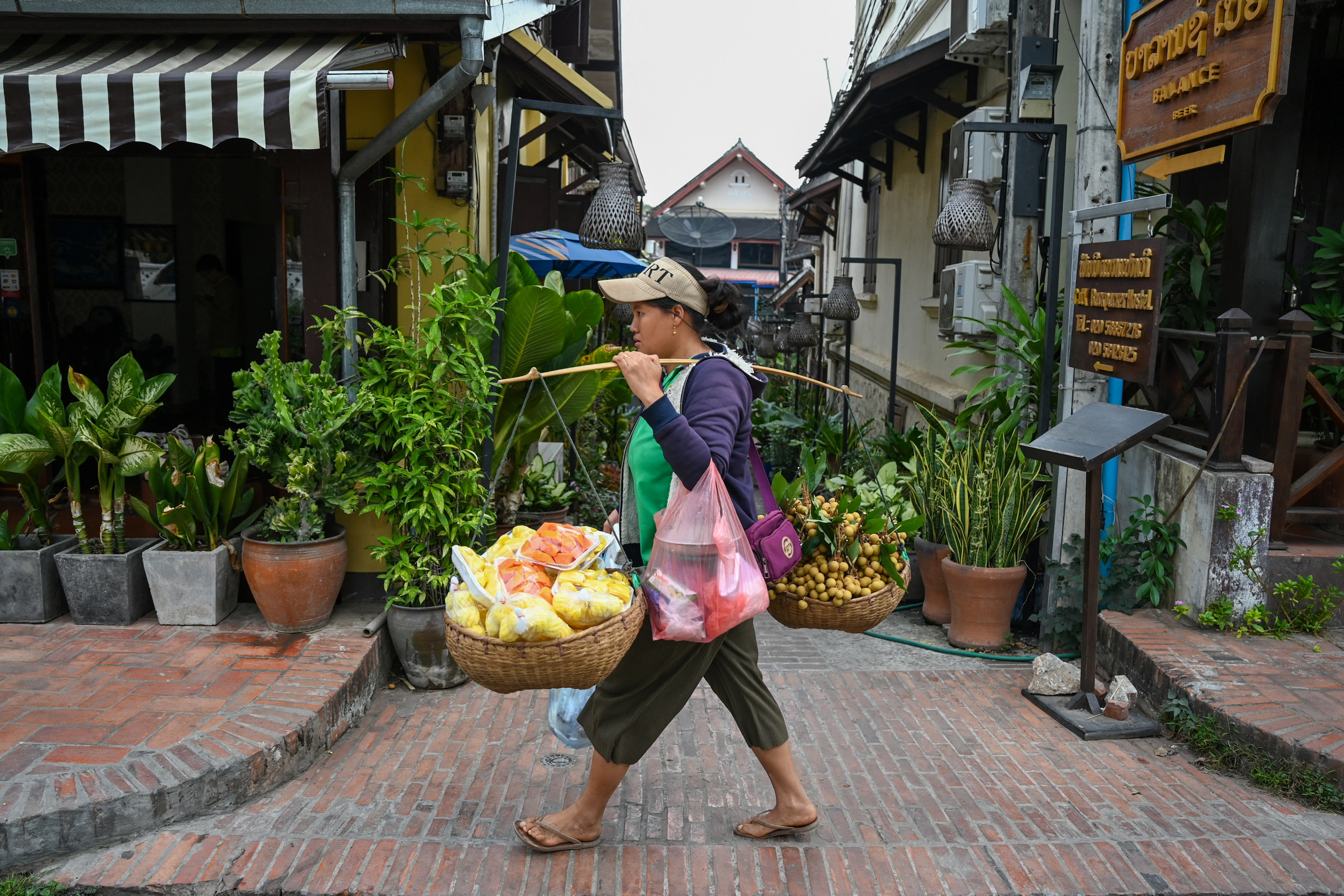 A vendor carries fresh produce for sale in Luang Prabang, Laos. Laotians grow their own food to reduce the need for expensive imported basic necessities. Photo: AFP