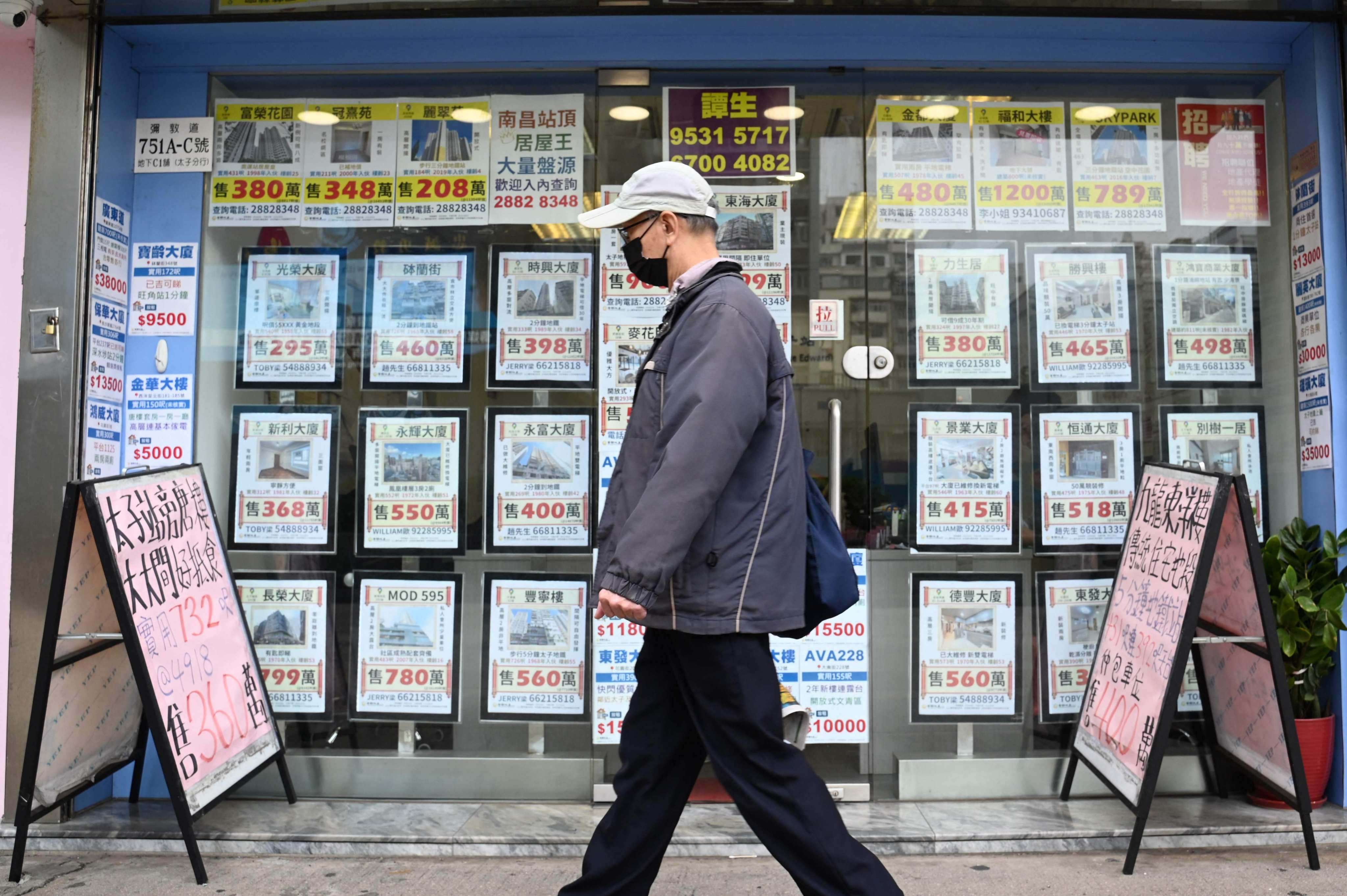 A pedestrian walks past a property agent in Hong Kong on February 28, 2024. Photo: AFP
