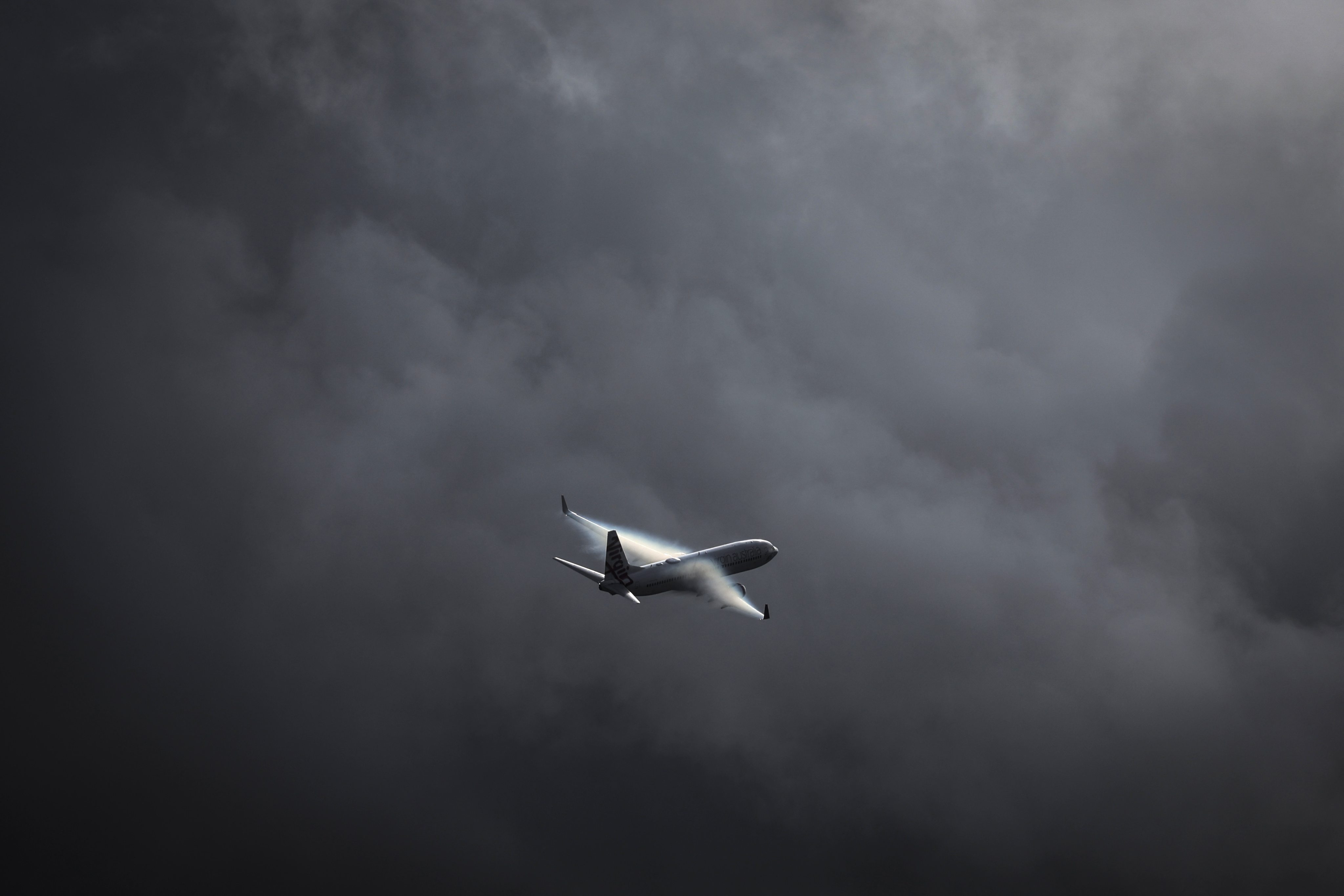 A passenger plane flies above Sydney International Airport as a storm approaches. The labour crisis on the ground is adding risk in the air during the post-Covid travel boom. Photo: AFP
