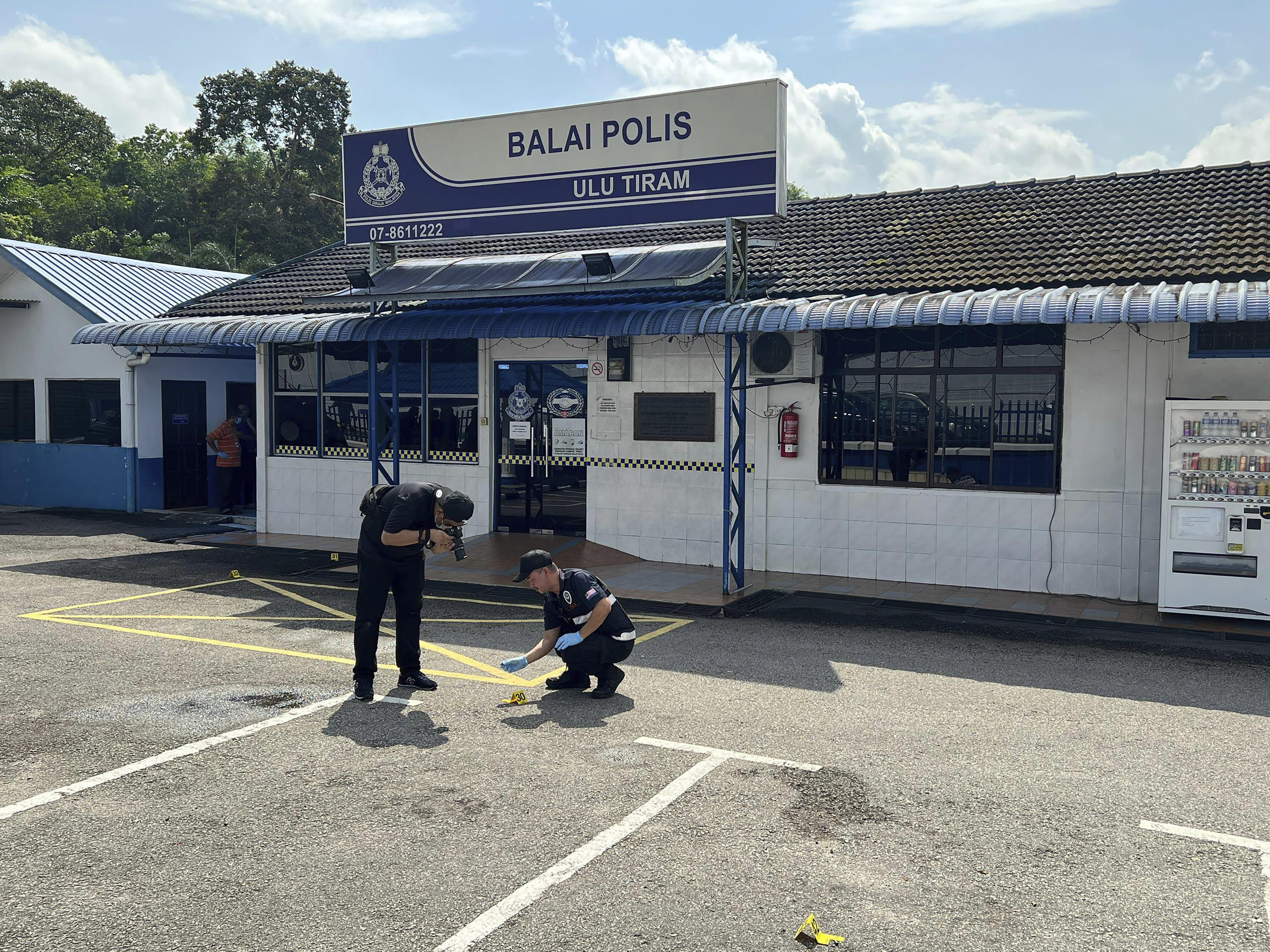 A police forensic team investigate outside a police station in southern Johor state that was stormed by a man with a machete on May 17. Photo :AP 