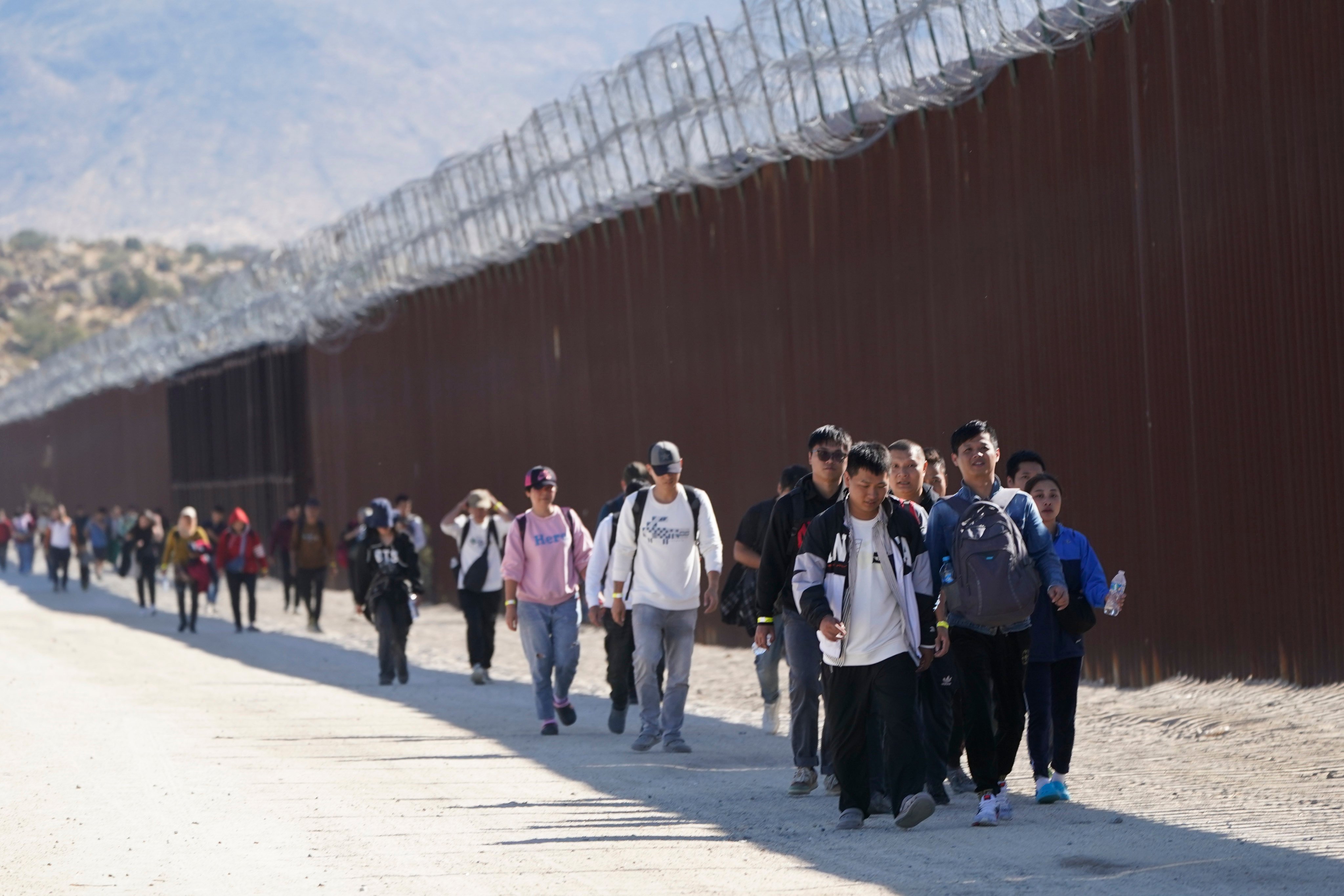A group of migrants, including many from China, walk along the wall in October 2023 after crossing the border from Mexico into California to seek asylum. Photo: AP