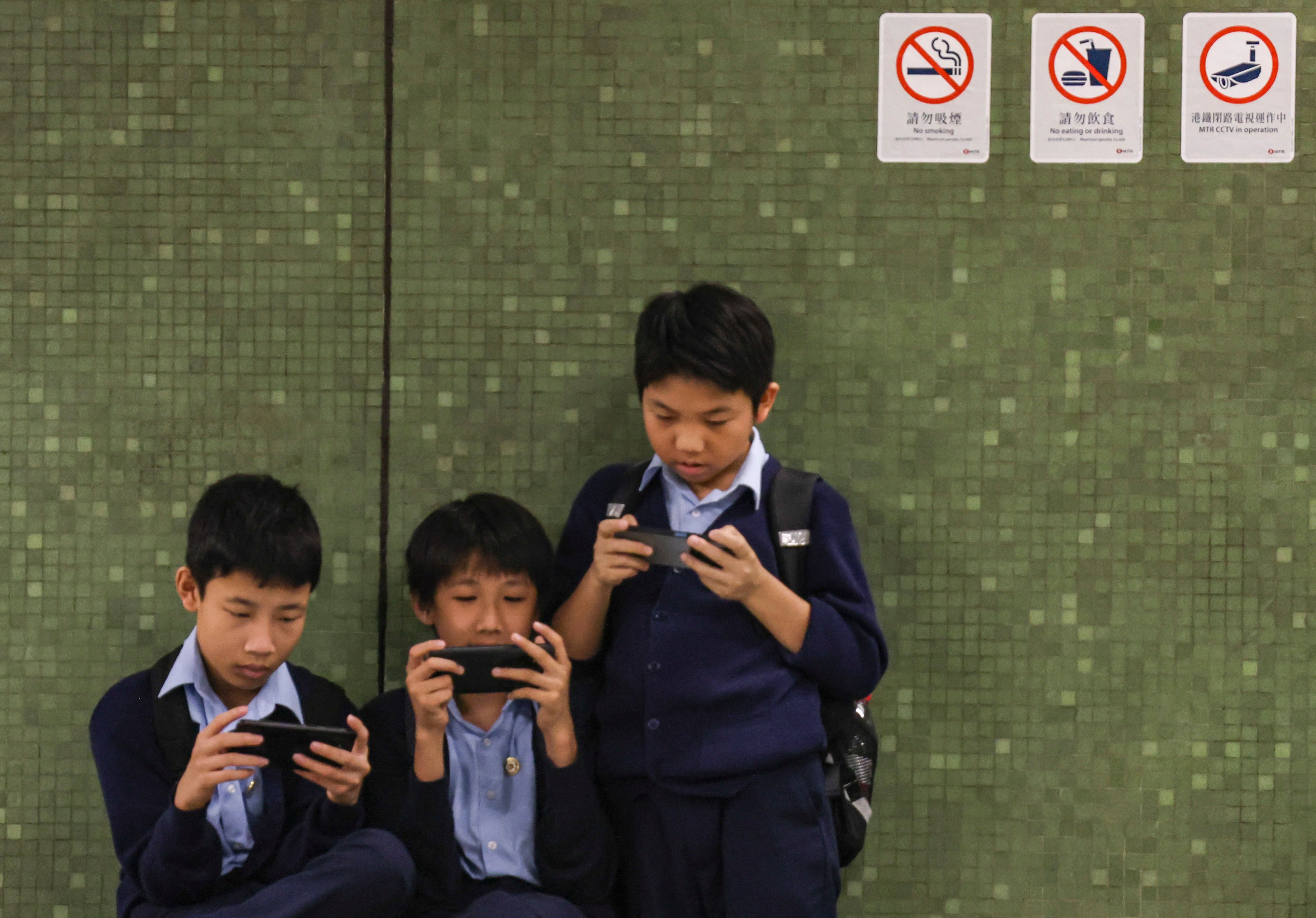 Children on their phones on the platform of Lok Fu MTR station on June 13. The US surgeon general is calling for warning labels to be applied to social media platforms, sparking discussion over the issue in Hong Kong. Photo: Jelly Tse