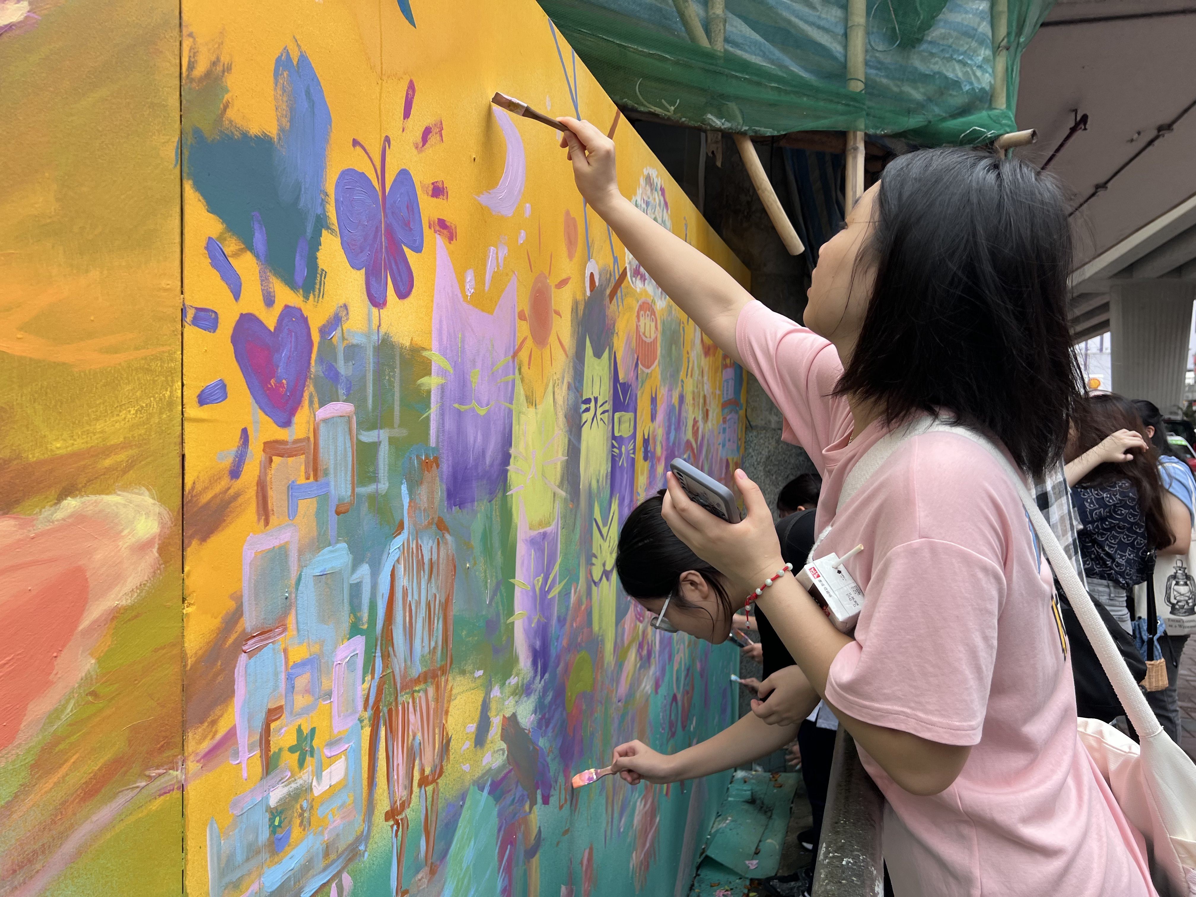 Mong Kok residents painting a mural on the hoarding of a construction site for a new building late last year in a community art project by the non-profit Art In Place. Photo: Art In Place Hong Kong