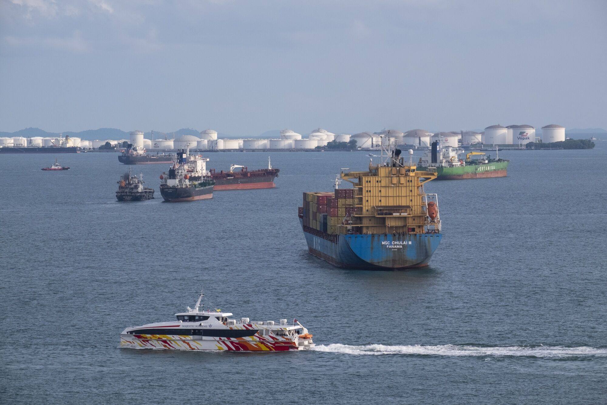 A ferry sails past a container ship and bulk carriers in Singapore. Photo: Bloomberg