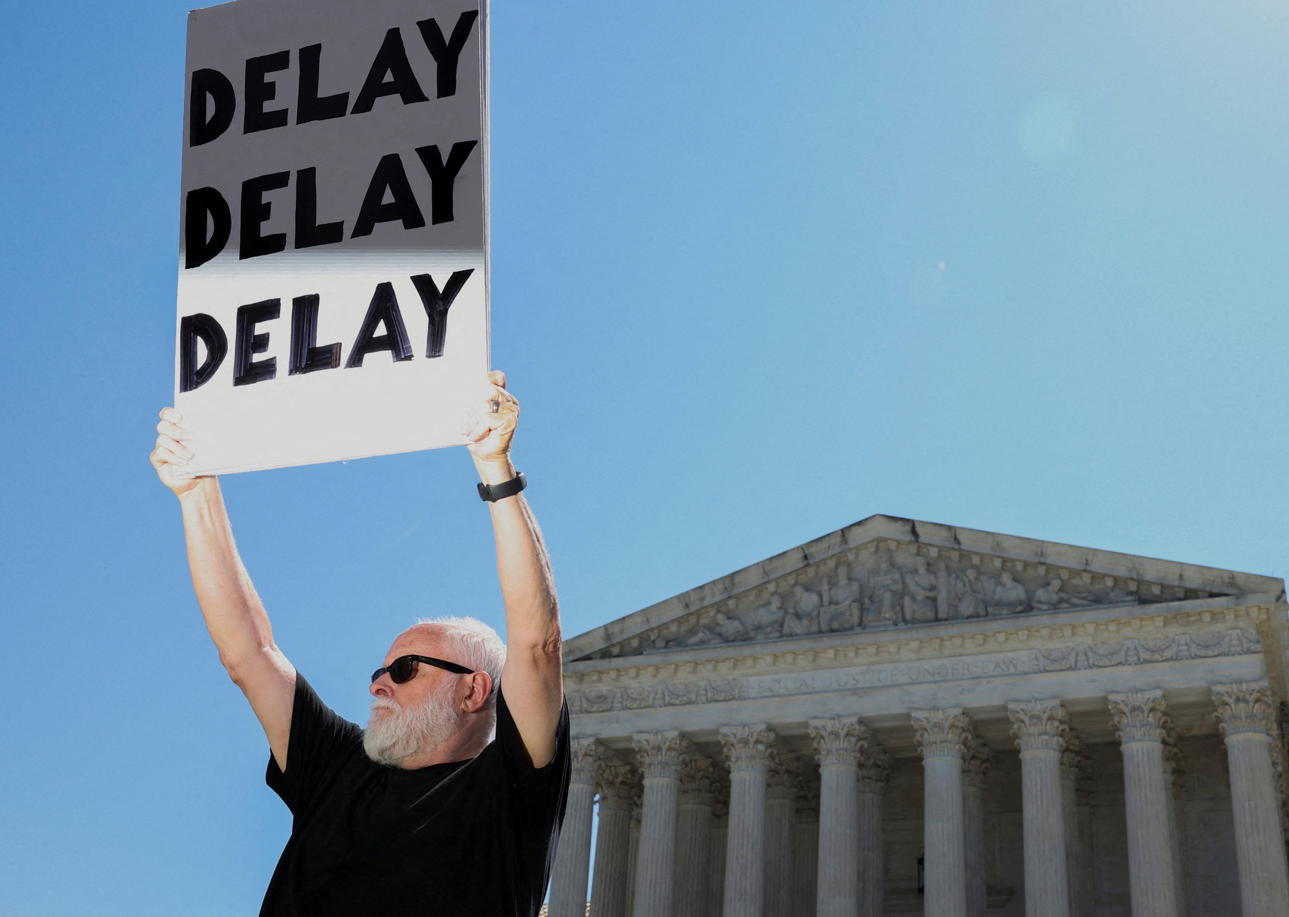 A protester holds a sign that reads “Delay Delay Delay” outside the US Supreme Court on Friday. Photo: AFP