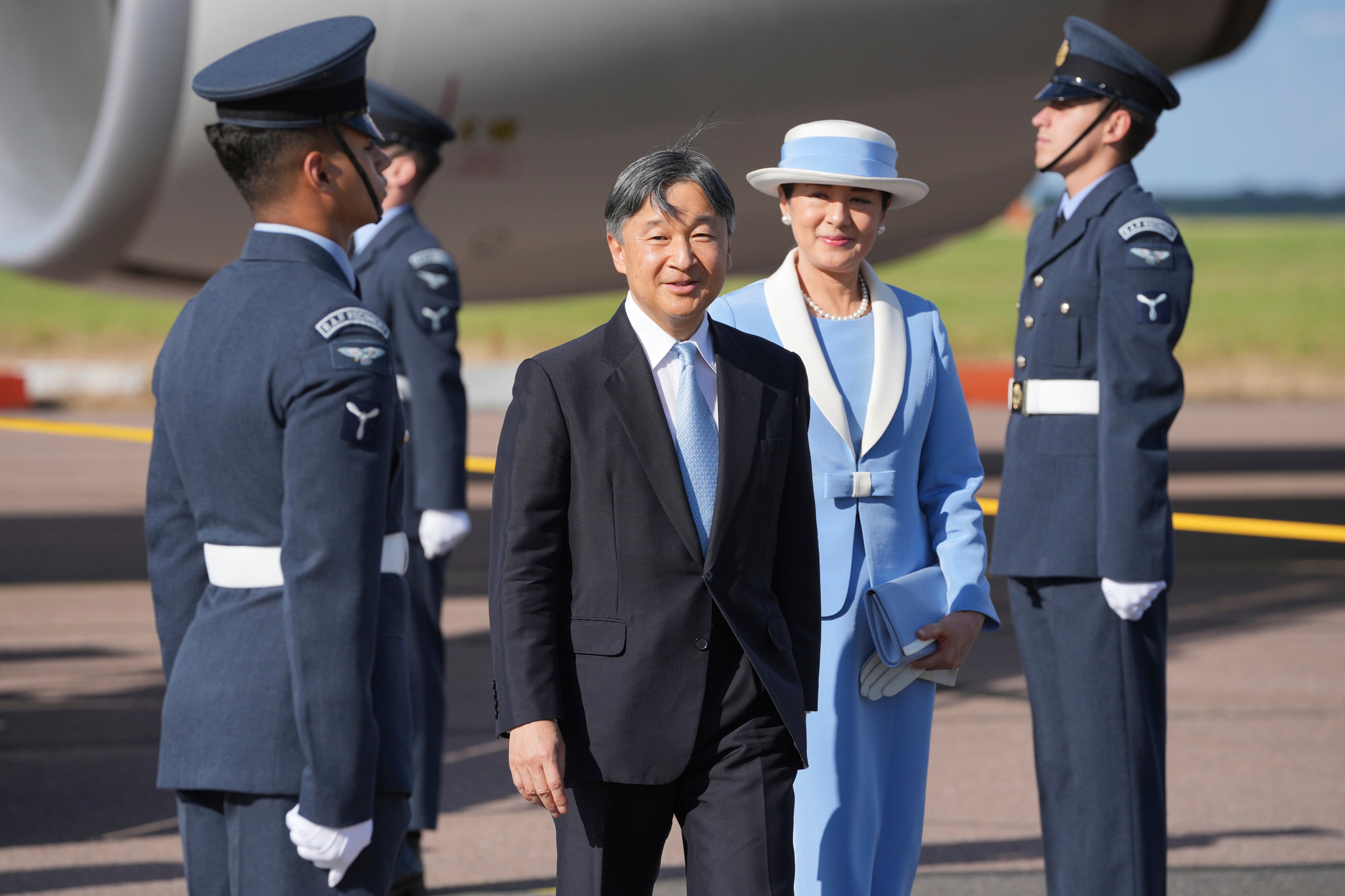 Emperor Naruhito and Empress Masako walk through a guard of honour after arriving at Stansted Airport on Saturday. Photo: AP,