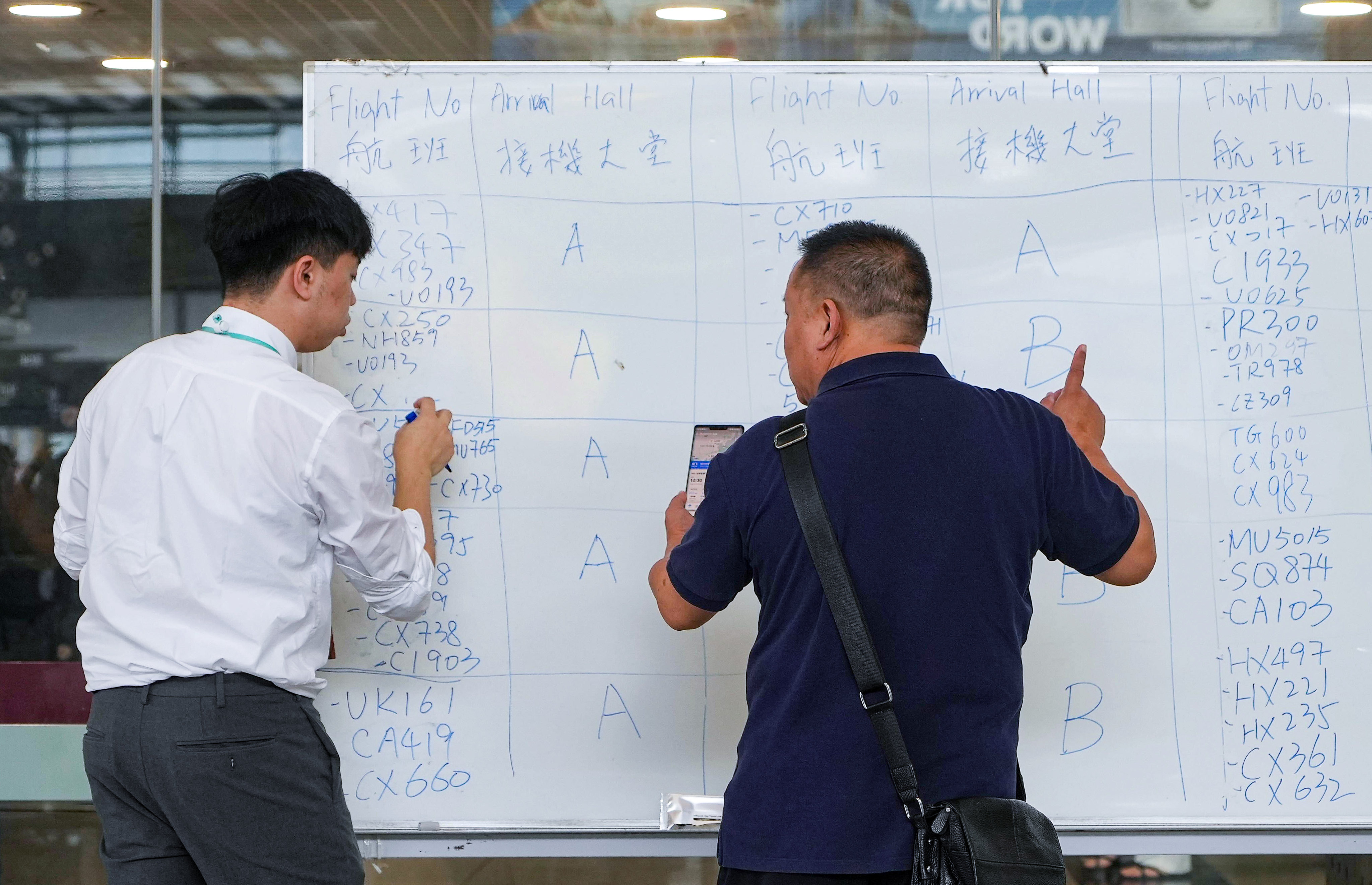 An airport staff member updates information on a whiteboard after a passenger information display screen failure on Sunday. Photo: Elson Li